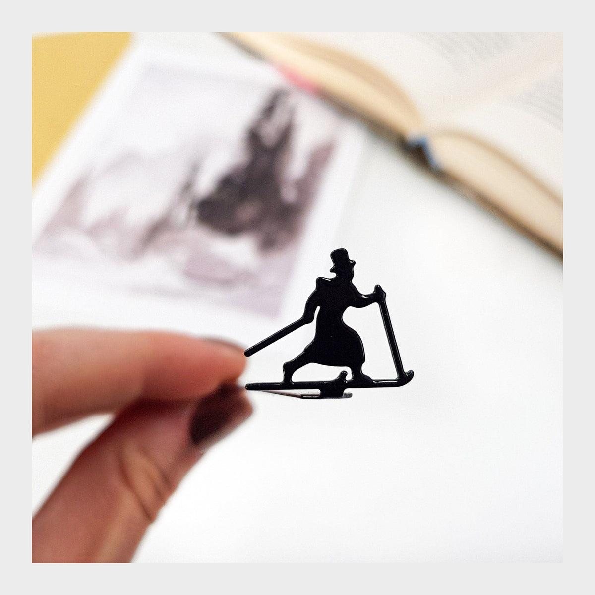 Skier in High Hat metal bookmark marking a page in an illustrated book