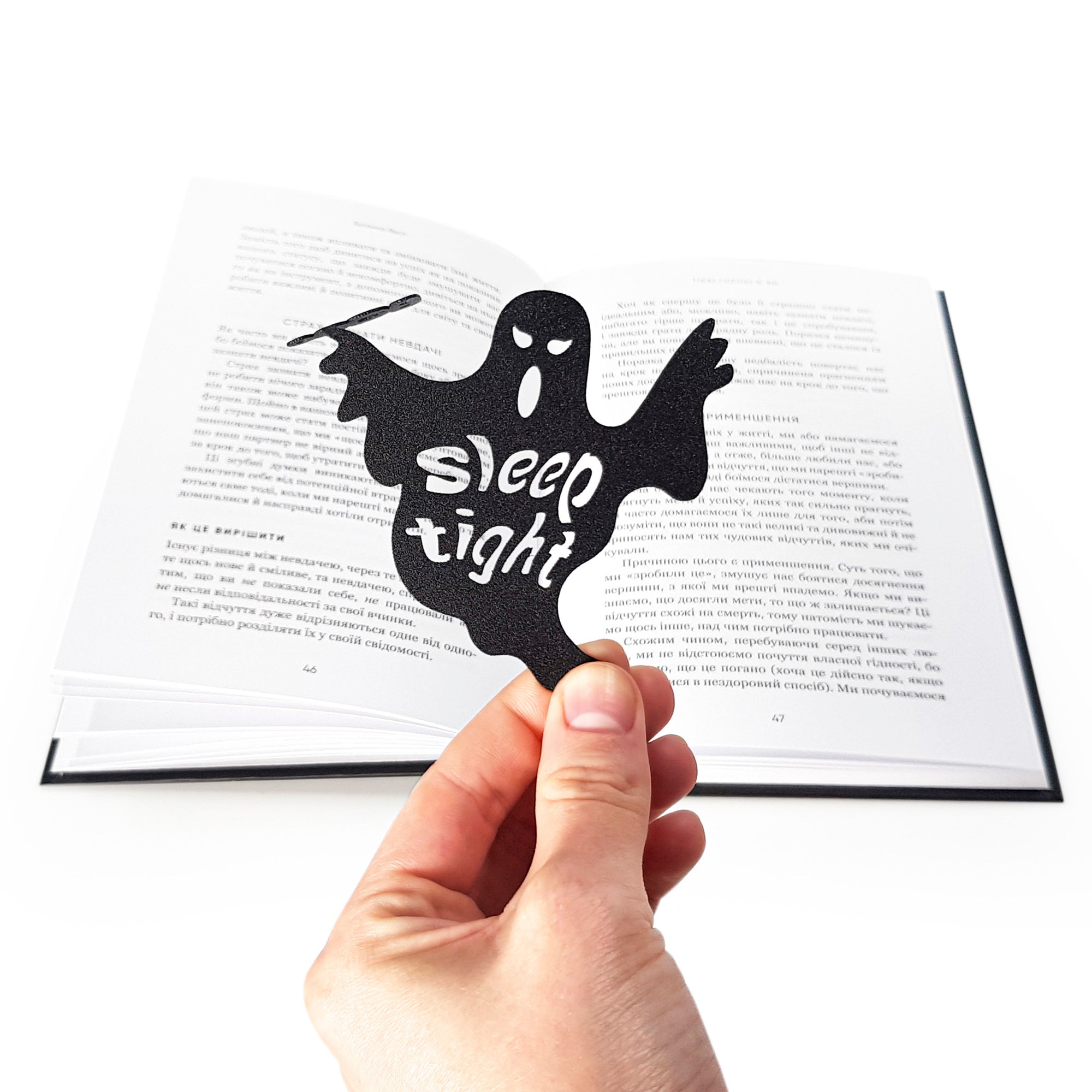 Black ghost-shaped bookmark with 'sleep tight' text held over an open book.  Designed and made by Atelier Article in Ukraine.