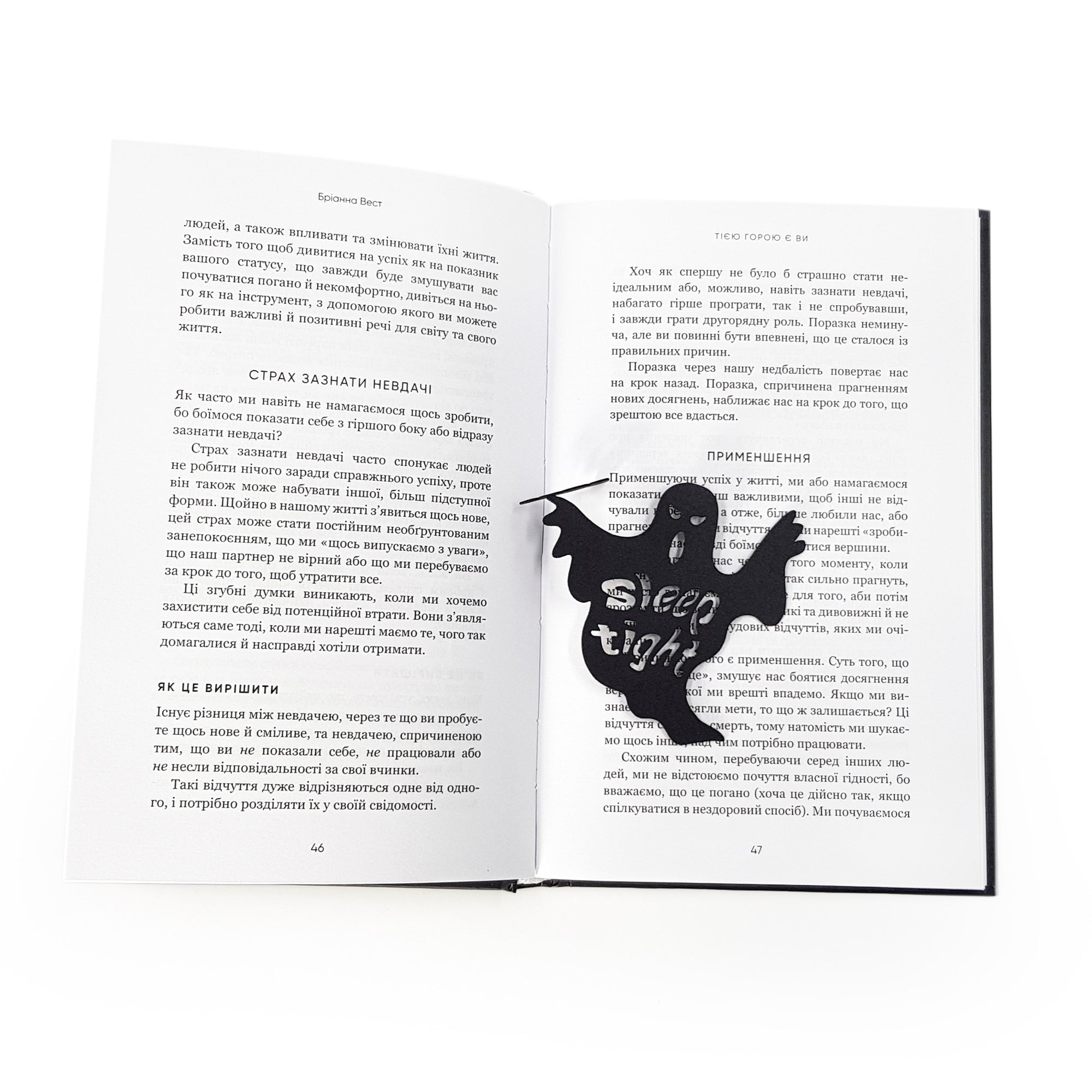 Open book with a black ghost-shaped bookmark inserted between the pages. The ghost features the cut-out phrase “Sleep Tight” 