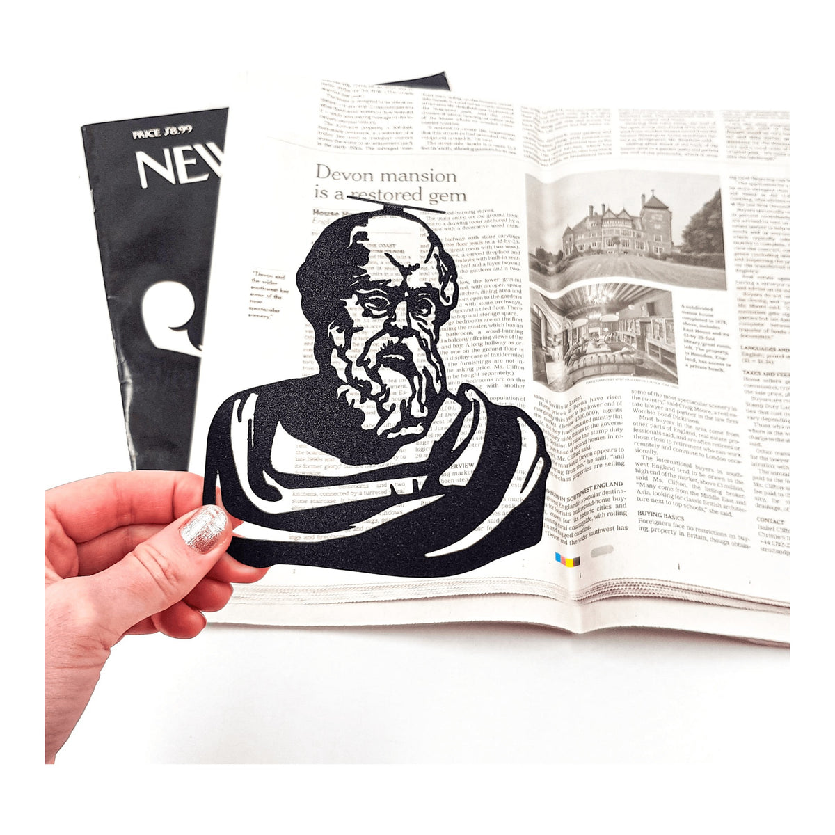 Socrates metal bookmark held in a hand above an open book
