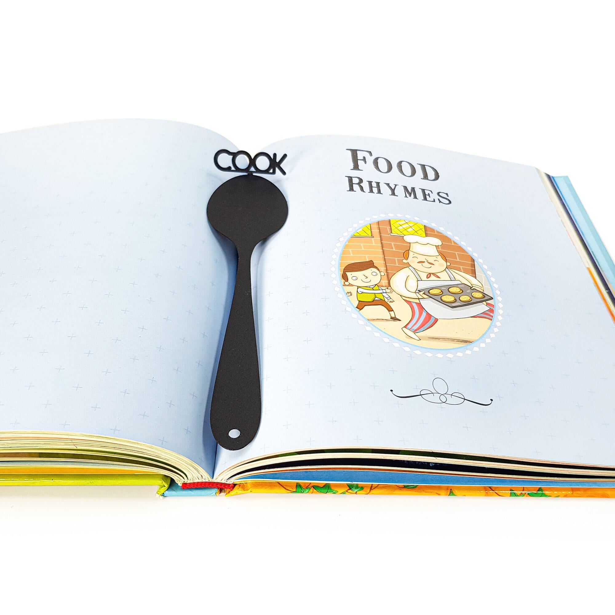Black metal spoon-shaped bookmark with the word “COOK” placed inside an open children’s book titled Food Rhymes, with colorful illustrations.