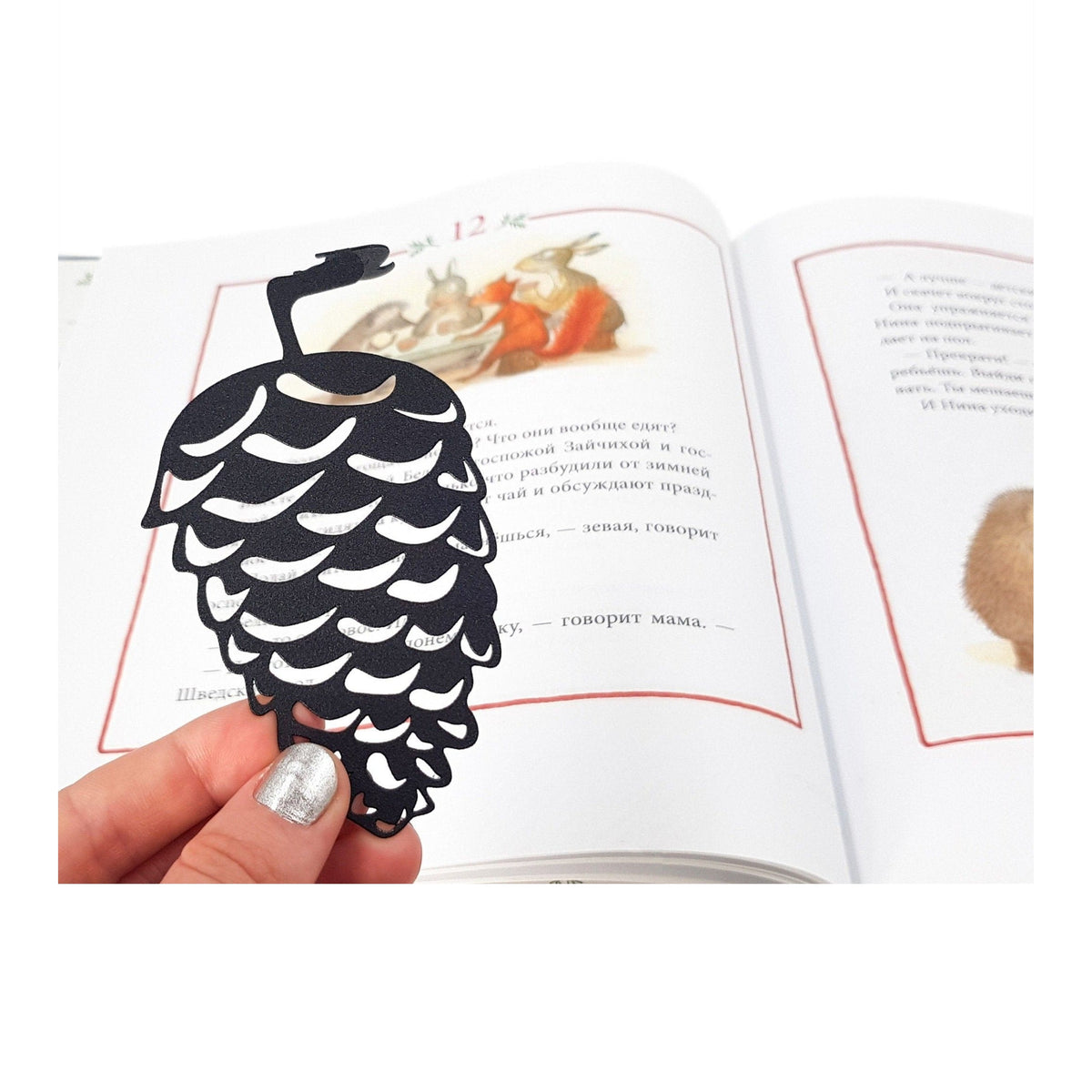Squirrel and a Pinecone metal bookmark resting on the pages of an open book