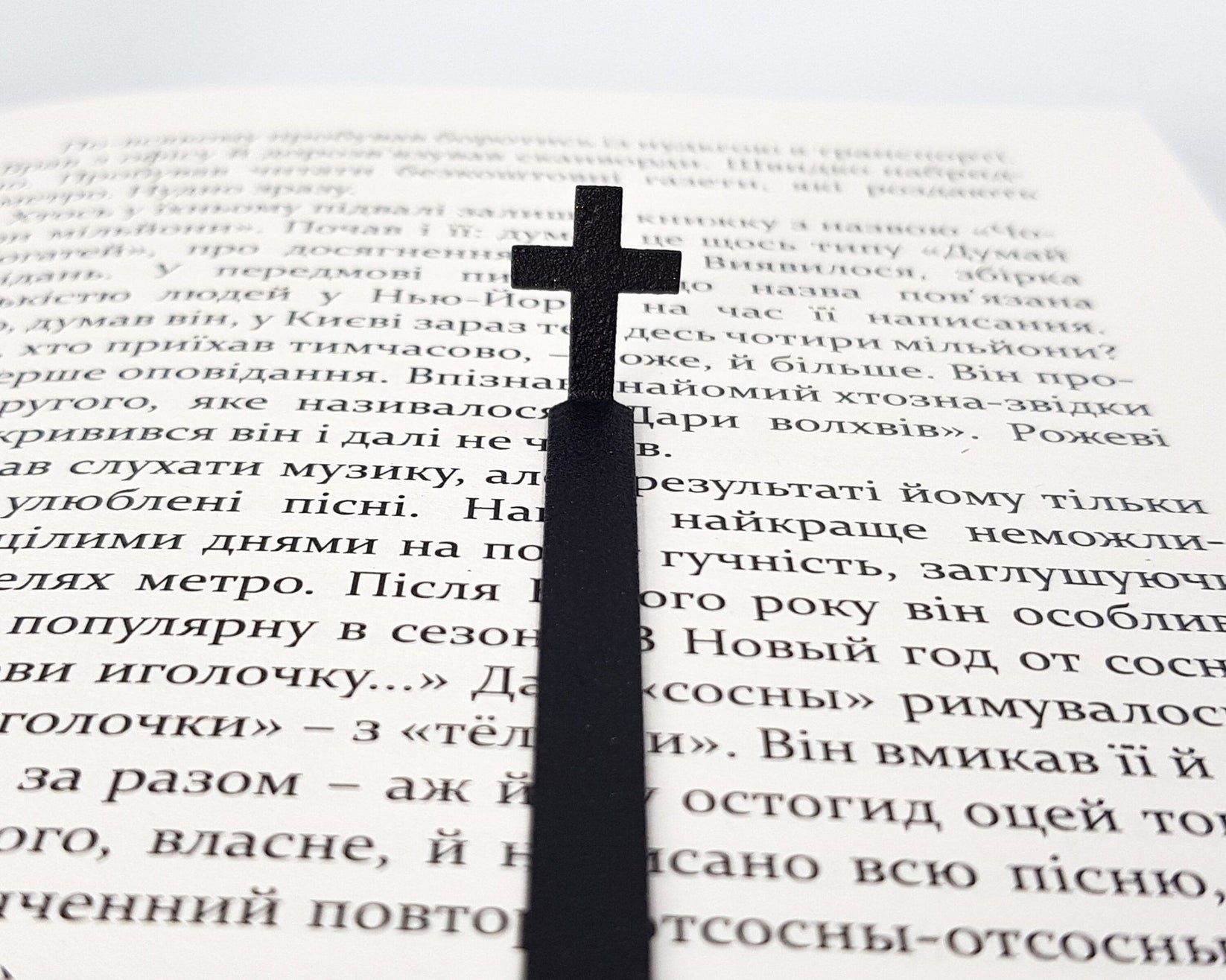 Straight Cross metal bookmark resting on the pages of an open book