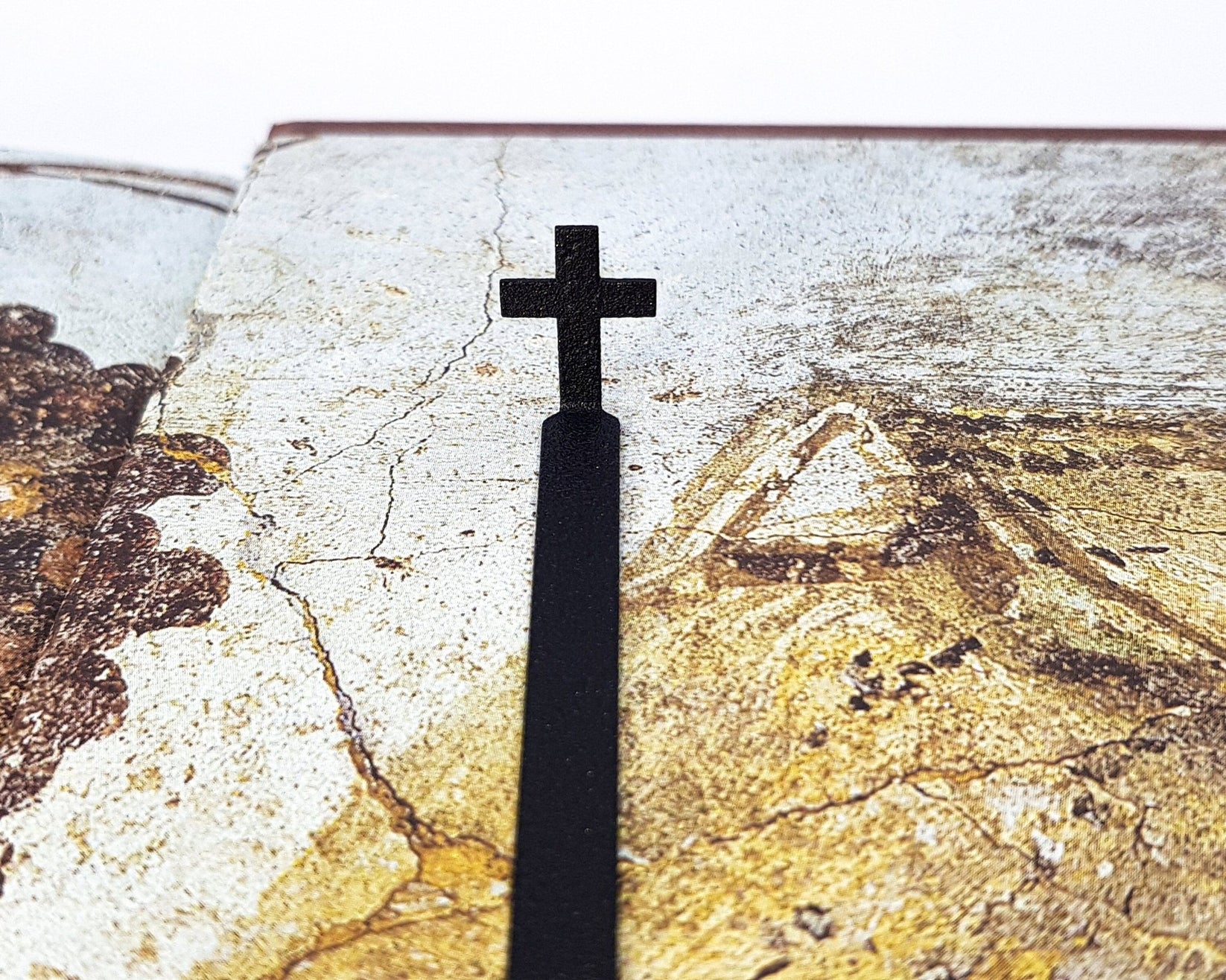Straight Cross metal bookmark against a coloured backdrop