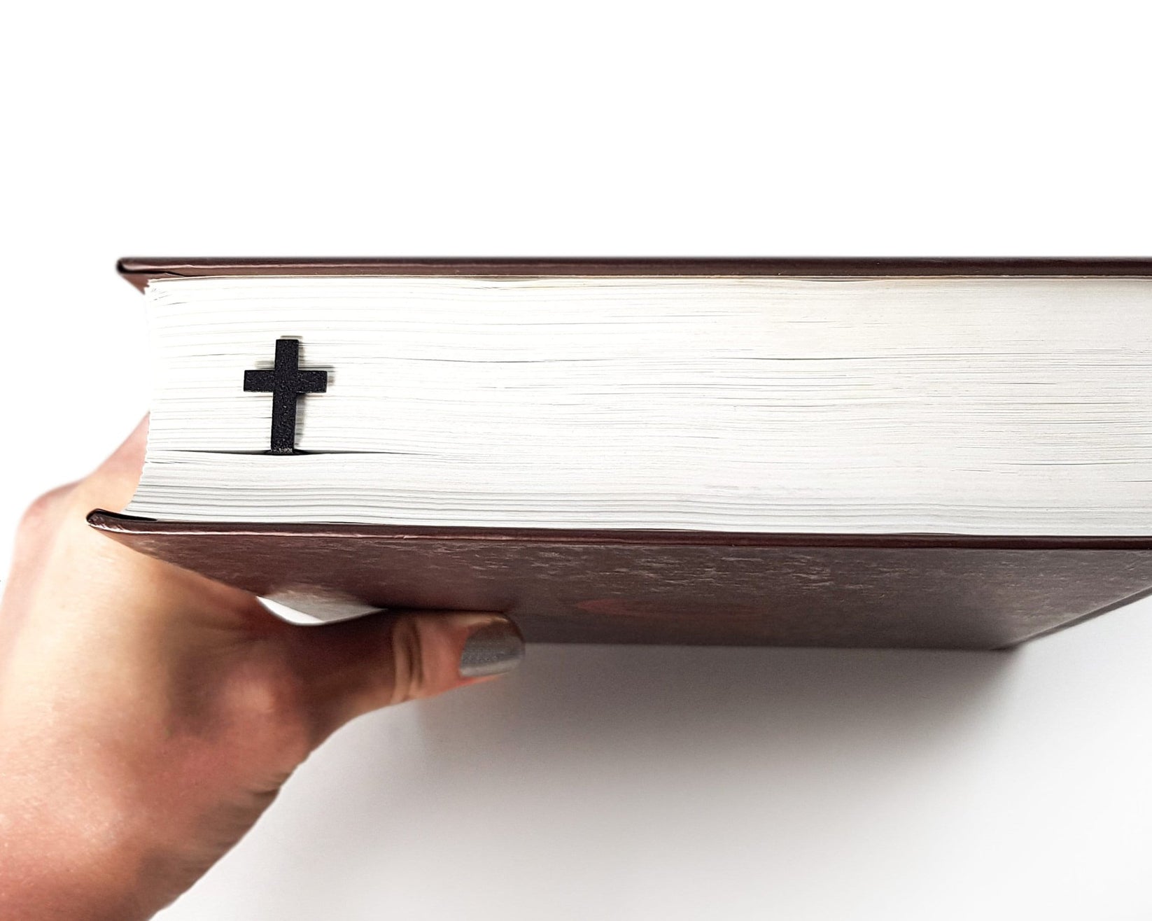 Straight Cross metal bookmark in a closed book, only its top showing above the pages