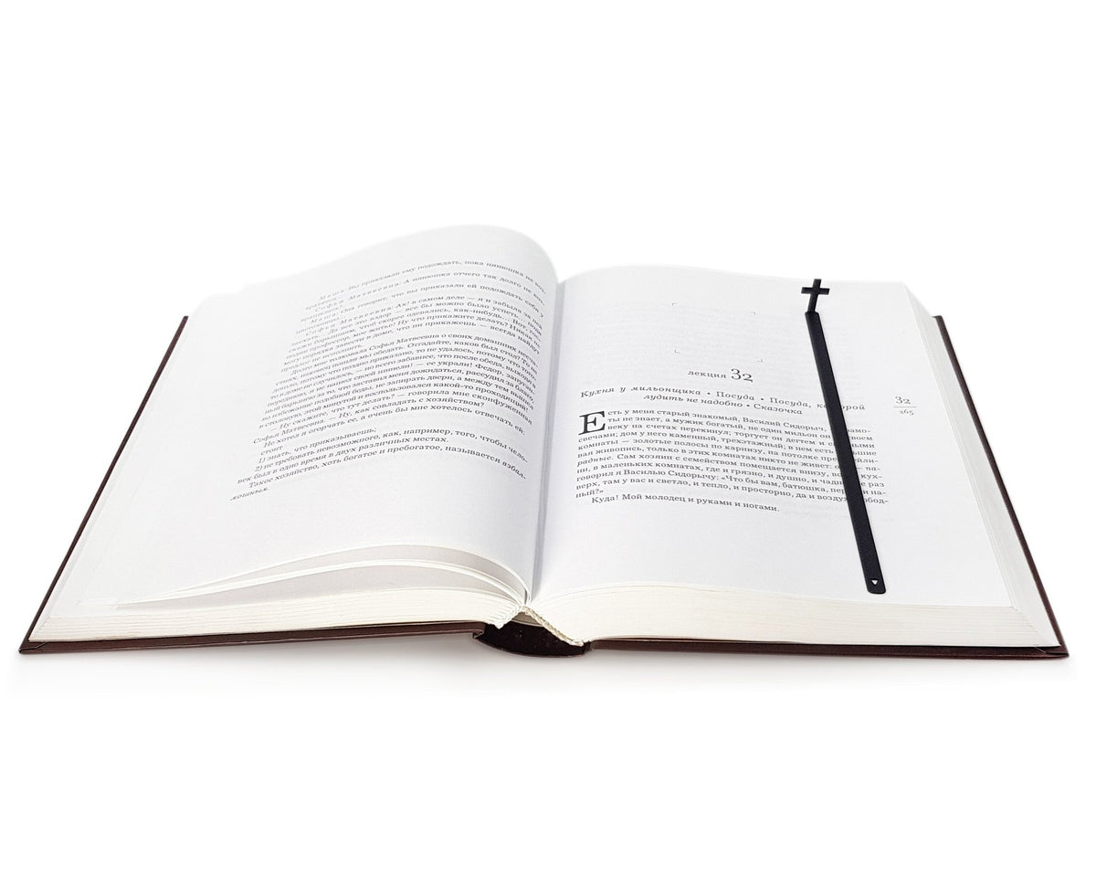 Straight Cross metal bookmark lying across the pages of an open book