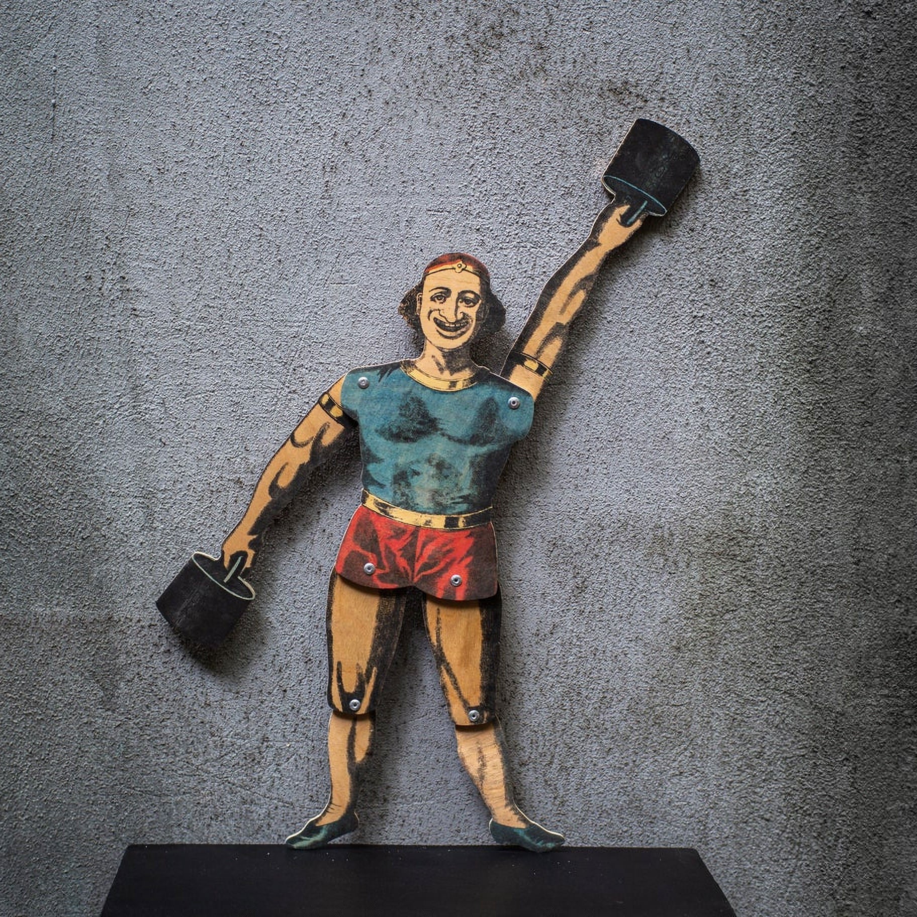 articulated plywood strongman puppet holding weights, vintage style with movable joints