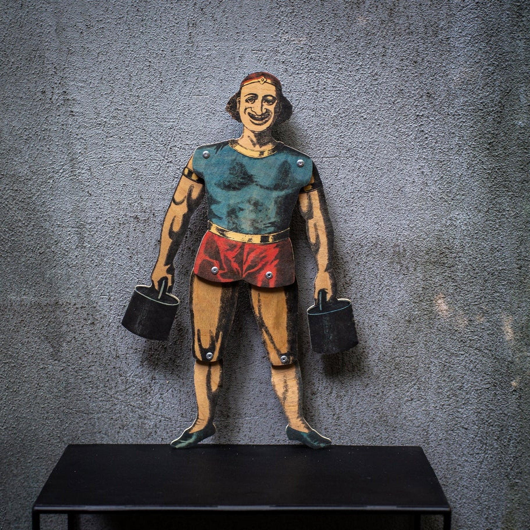 articulated plywood strongman puppet holding weights, vintage style with movable joints
