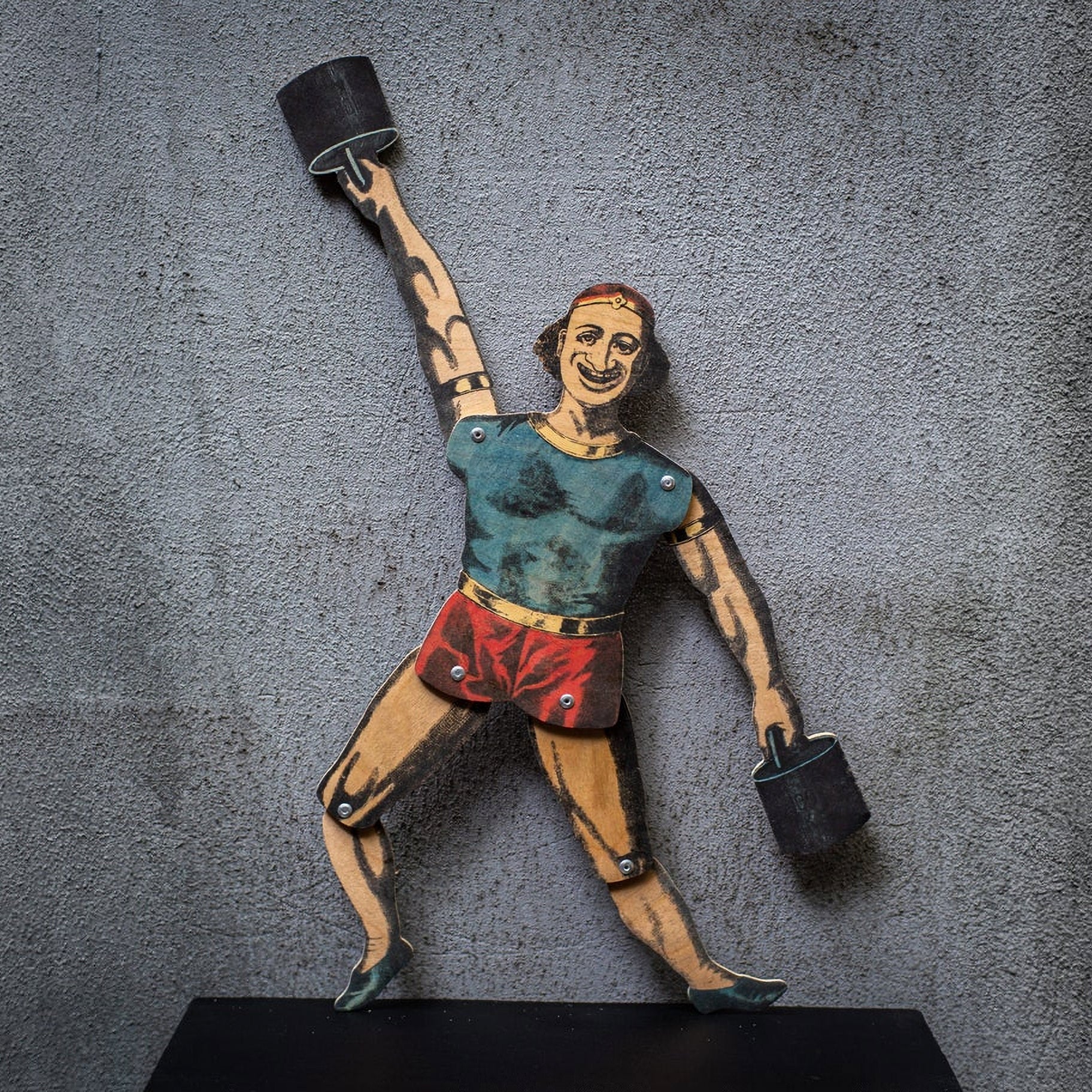 articulated plywood strongman puppet lifting weights, vintage style with movable joints