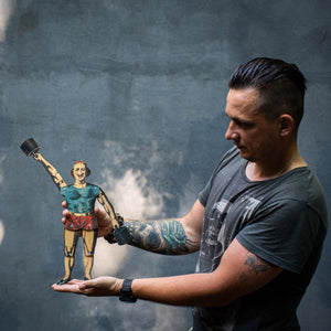 man holding articulated plywood strongman puppet with weights, vintage style design