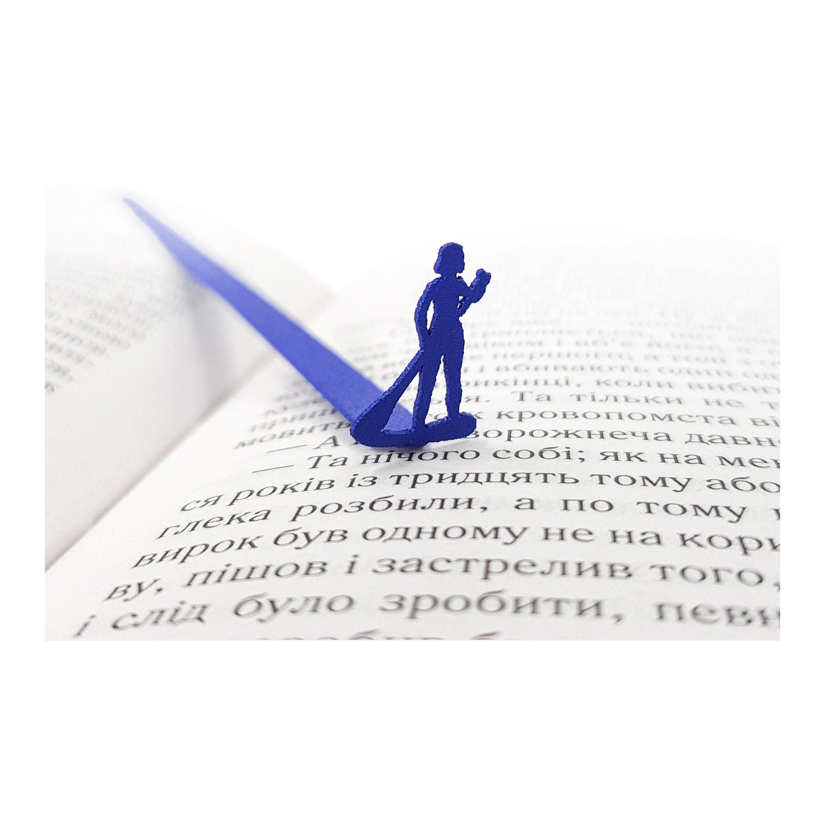 Surfer metal bookmark in blue resting on the pages of an open book