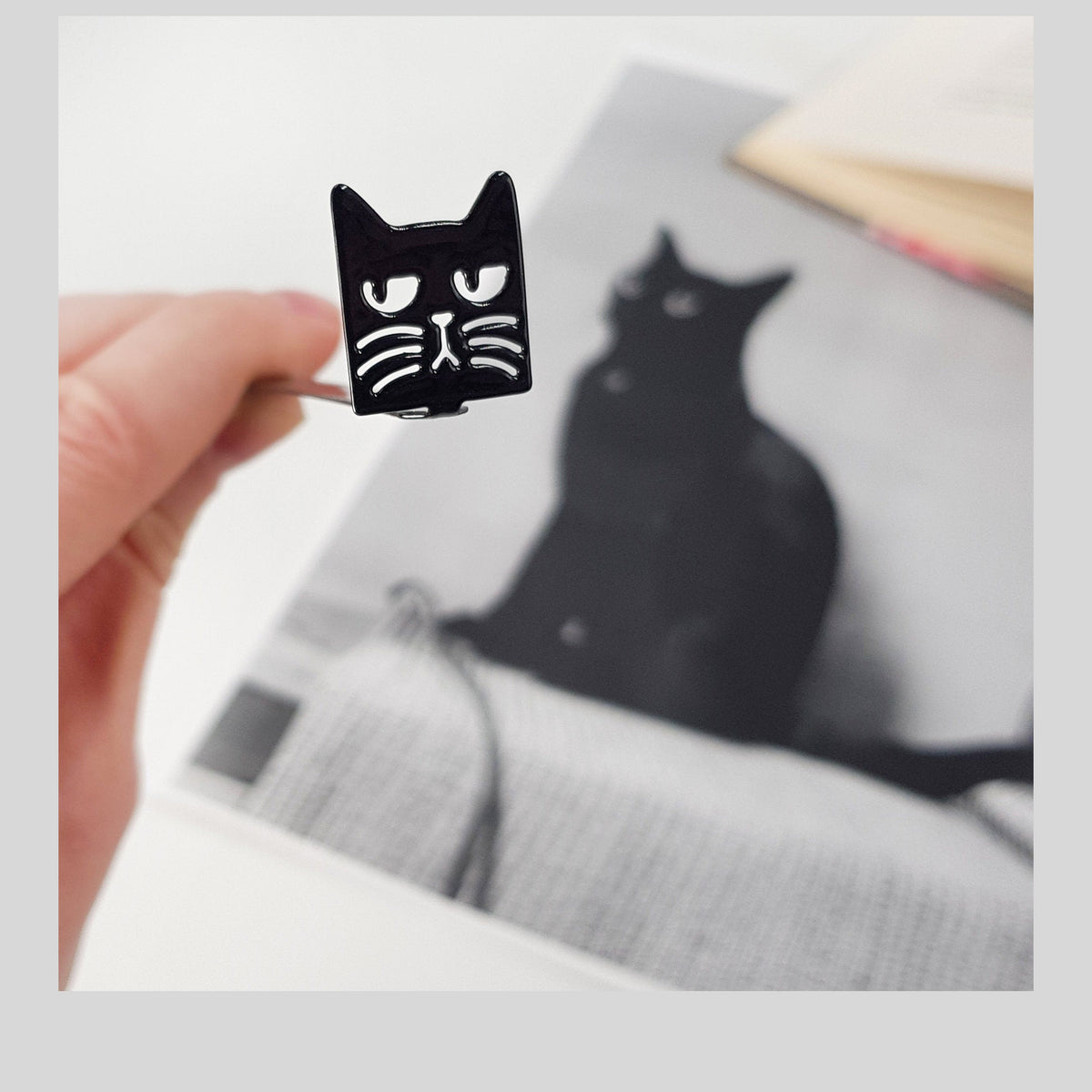 Suspicious Cat metal bookmark marking a page in an illustrated book