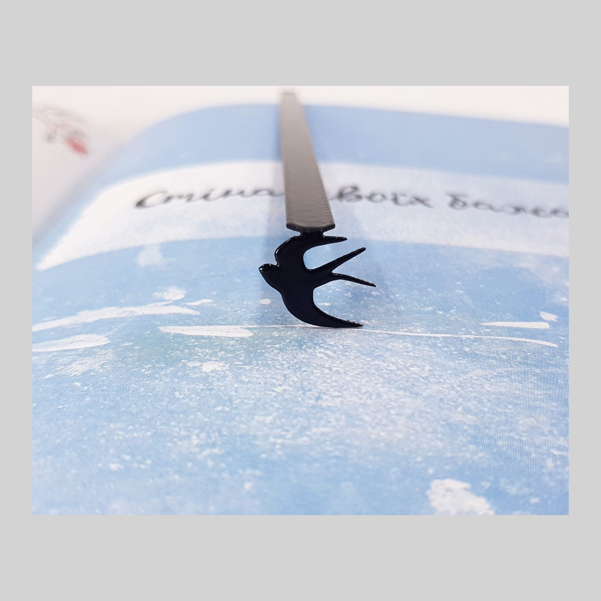 Swallow metal bookmark on a coloured background