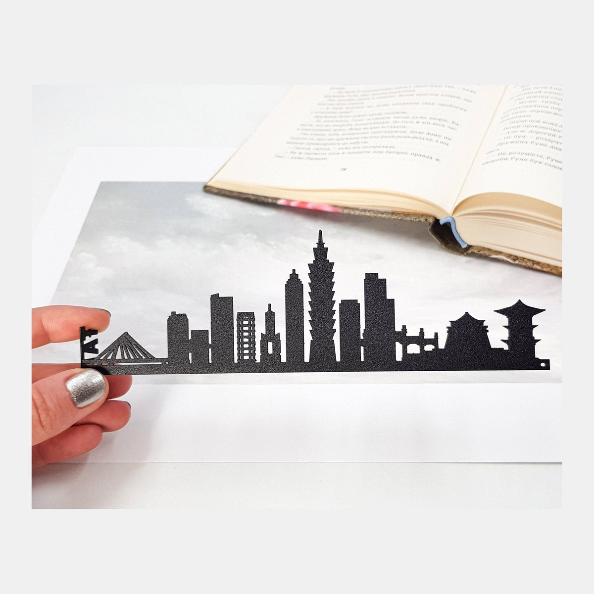 Taipei metal bookmark held in a hand above an open book