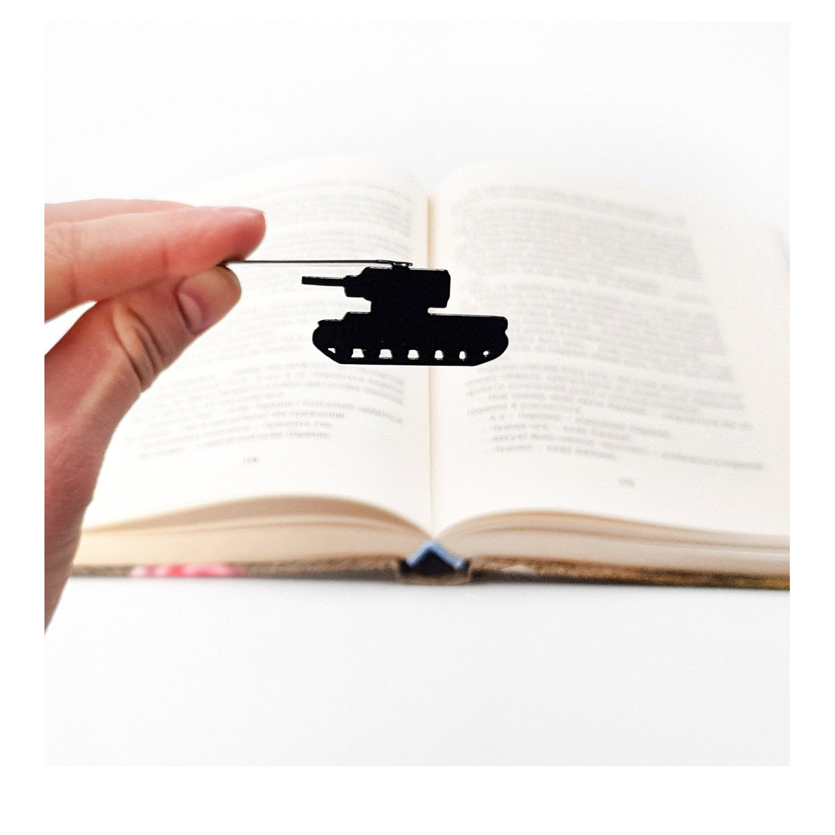 Tank metal bookmark held in a hand above an open book