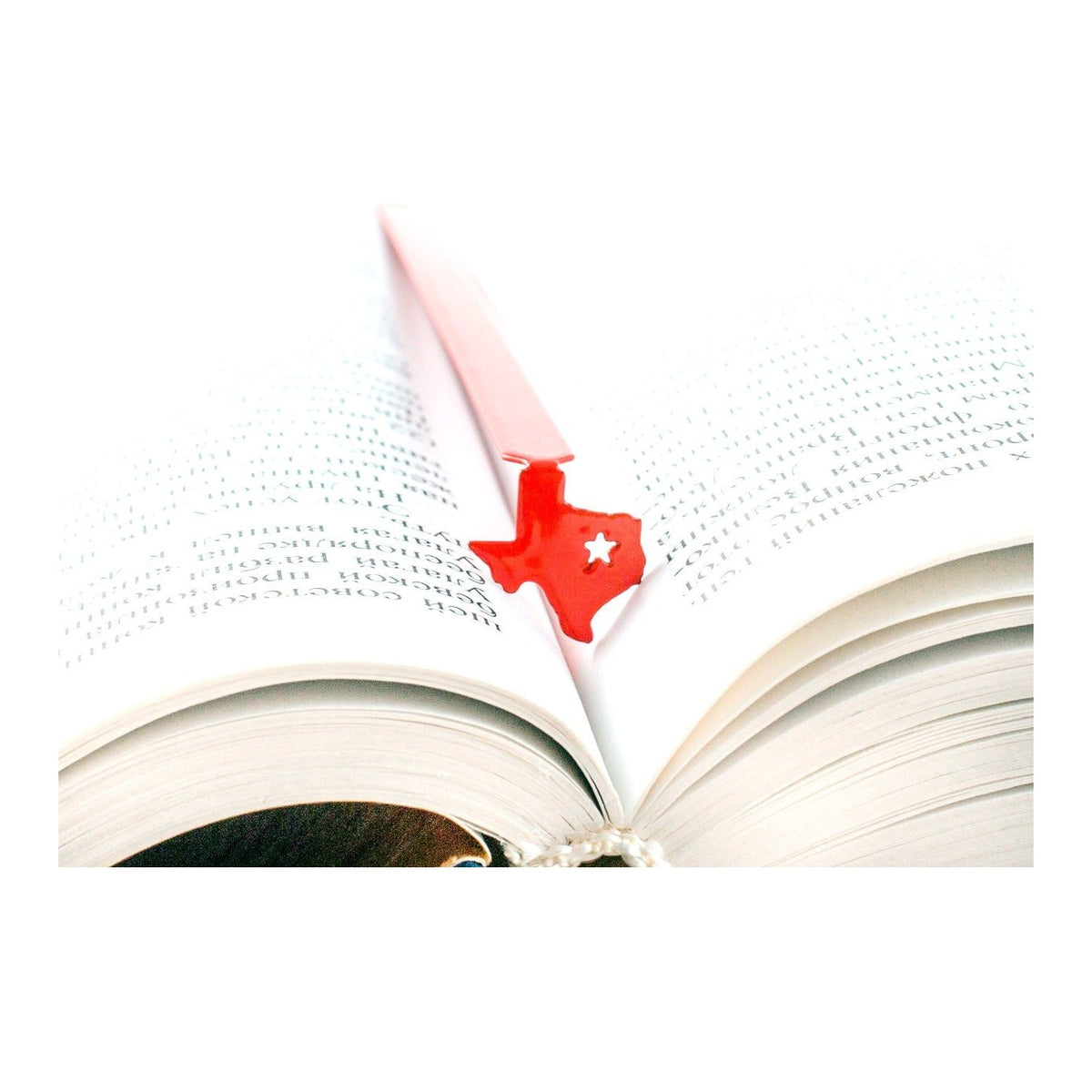 Texas metal bookmark in red resting on the pages of an open book