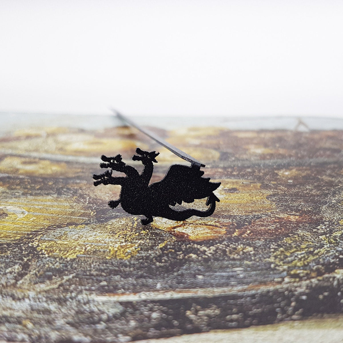 Three Headed Dragon metal bookmark on a coloured background