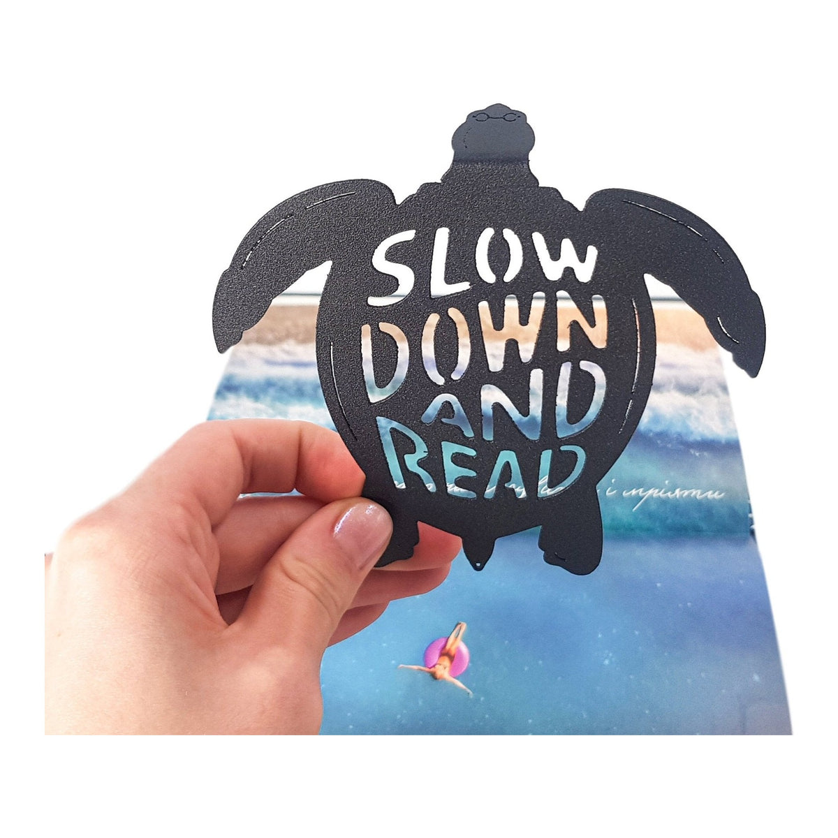 Slow Down and Read turtle metal bookmark marking a page in an illustrated book