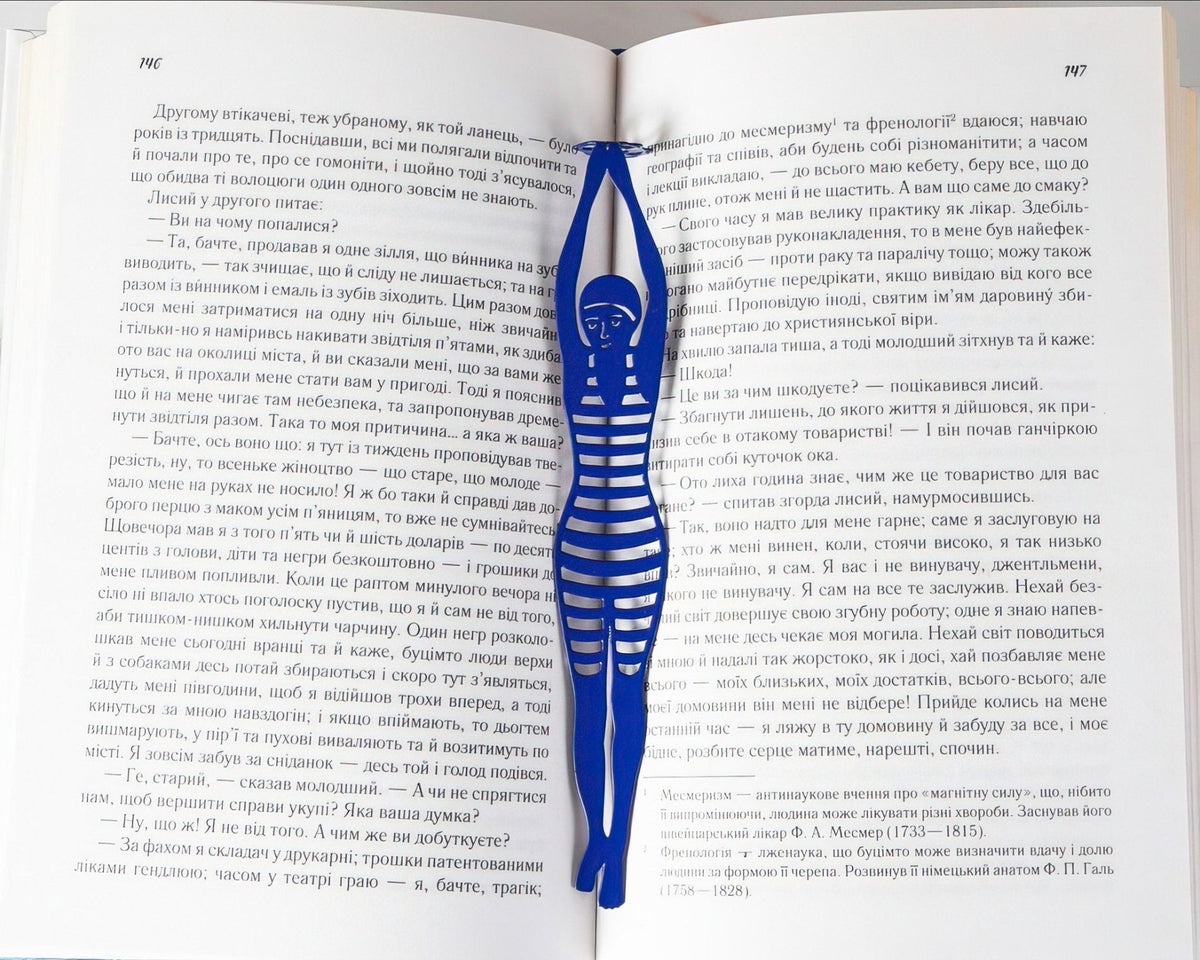 Diving Girl metal bookmark in blue resting on the pages of an open book