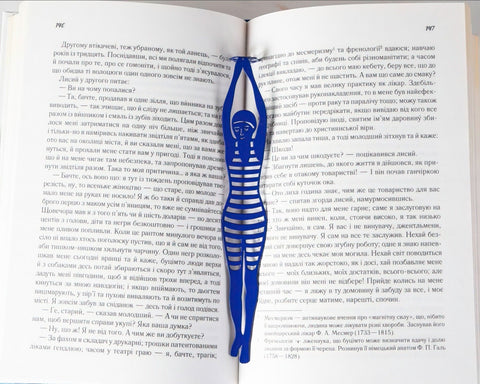 Diving Girl metal bookmark in blue resting on the pages of an open book