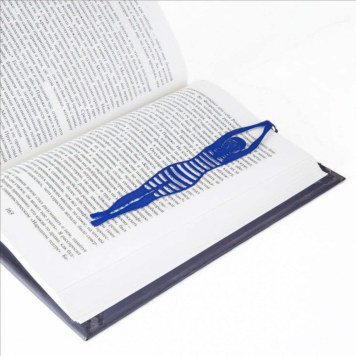Diving Girl metal bookmark in blue marking a page in an open book