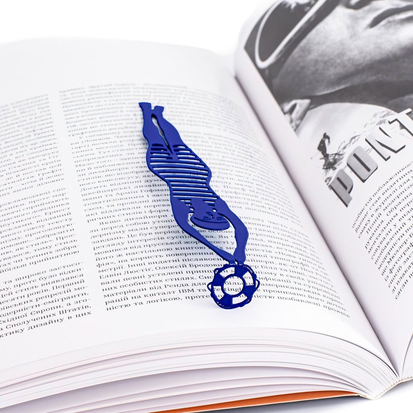 Diving Girl metal bookmark in blue marking a page in an illustrated book