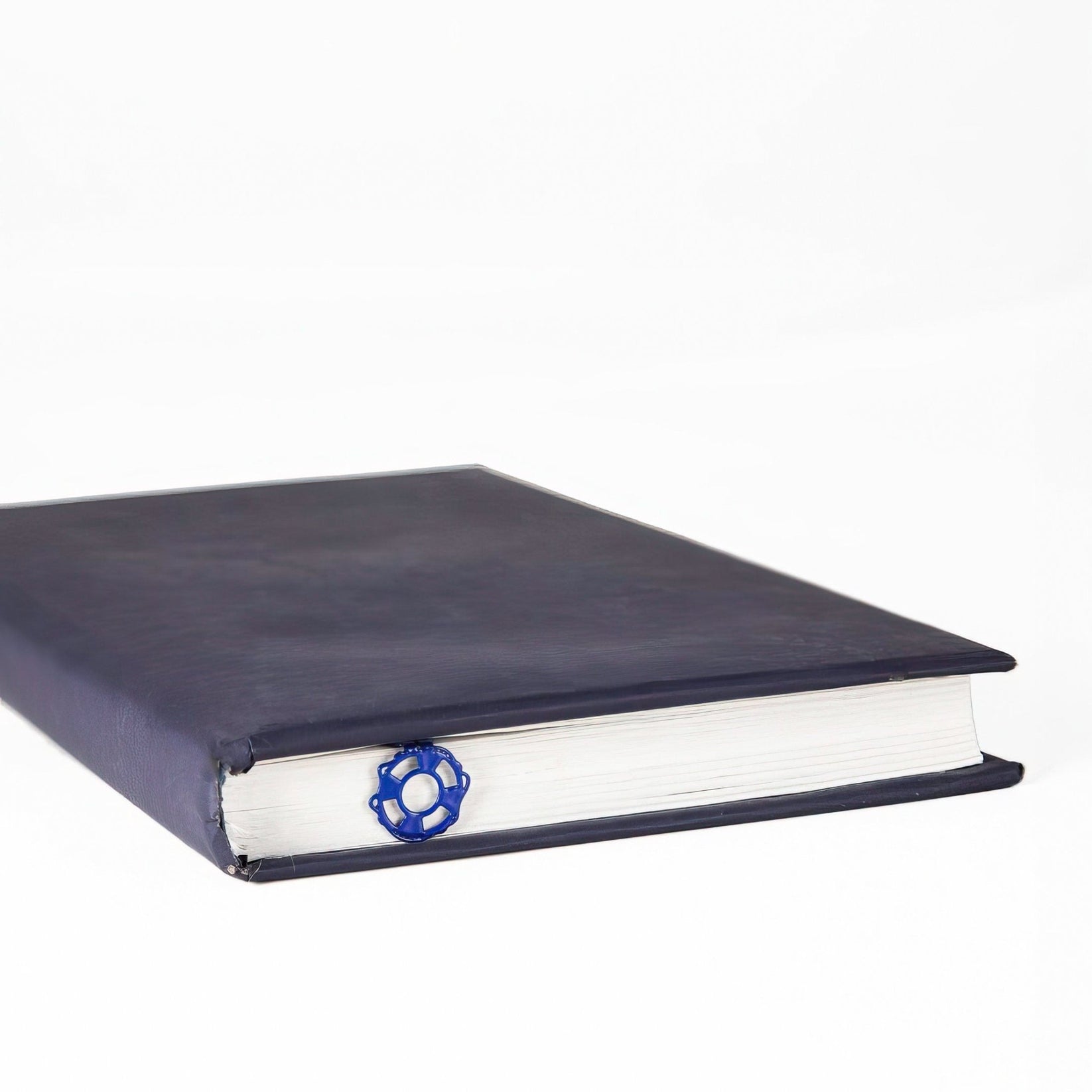 Diving Girl metal bookmark in blue in a closed book, only its top showing above the pages