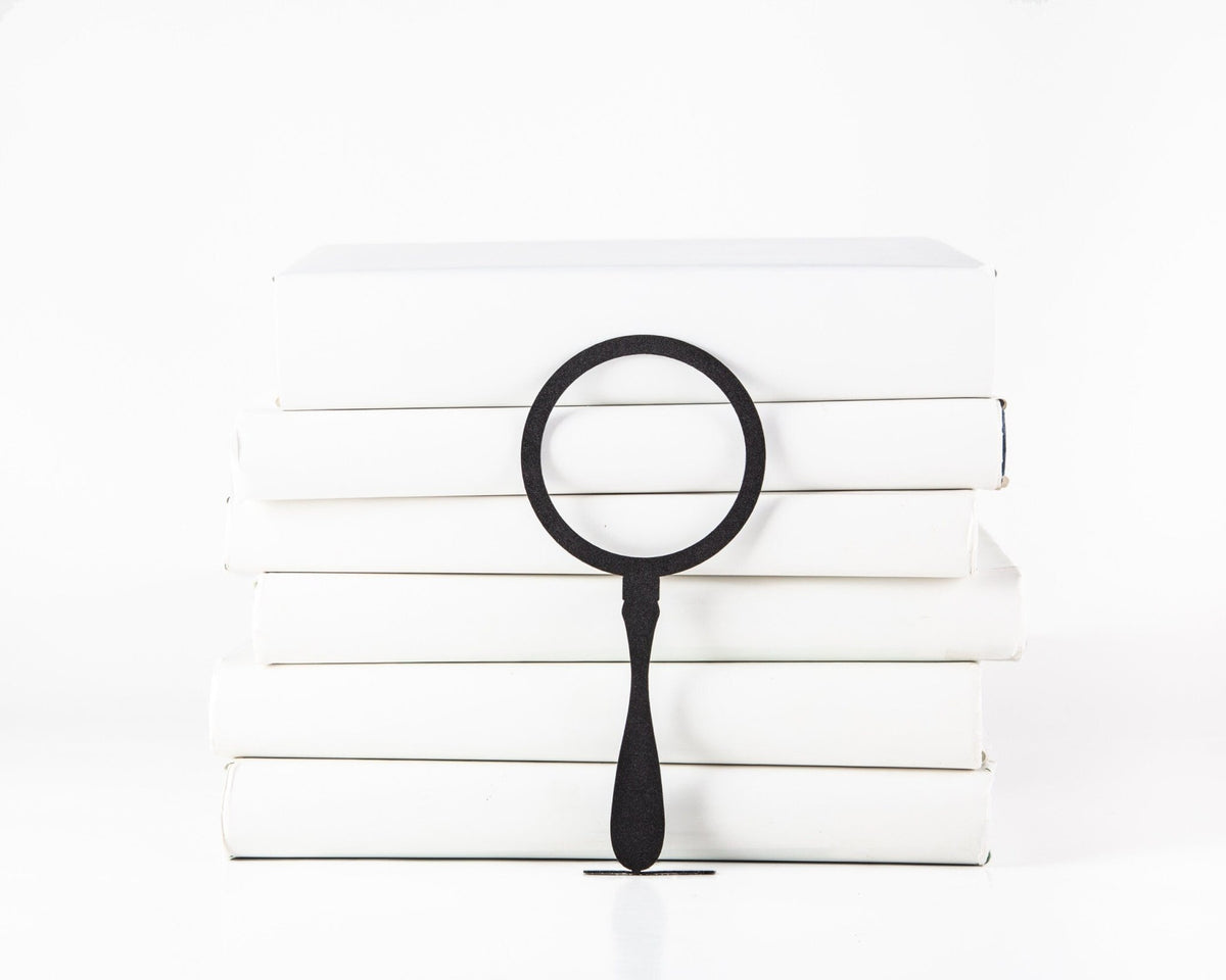 Magnifying Glass metal bookmark shown with a stack of books