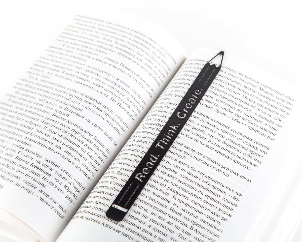 Pencil Read, Think, Create metal bookmark resting on the pages of an open book