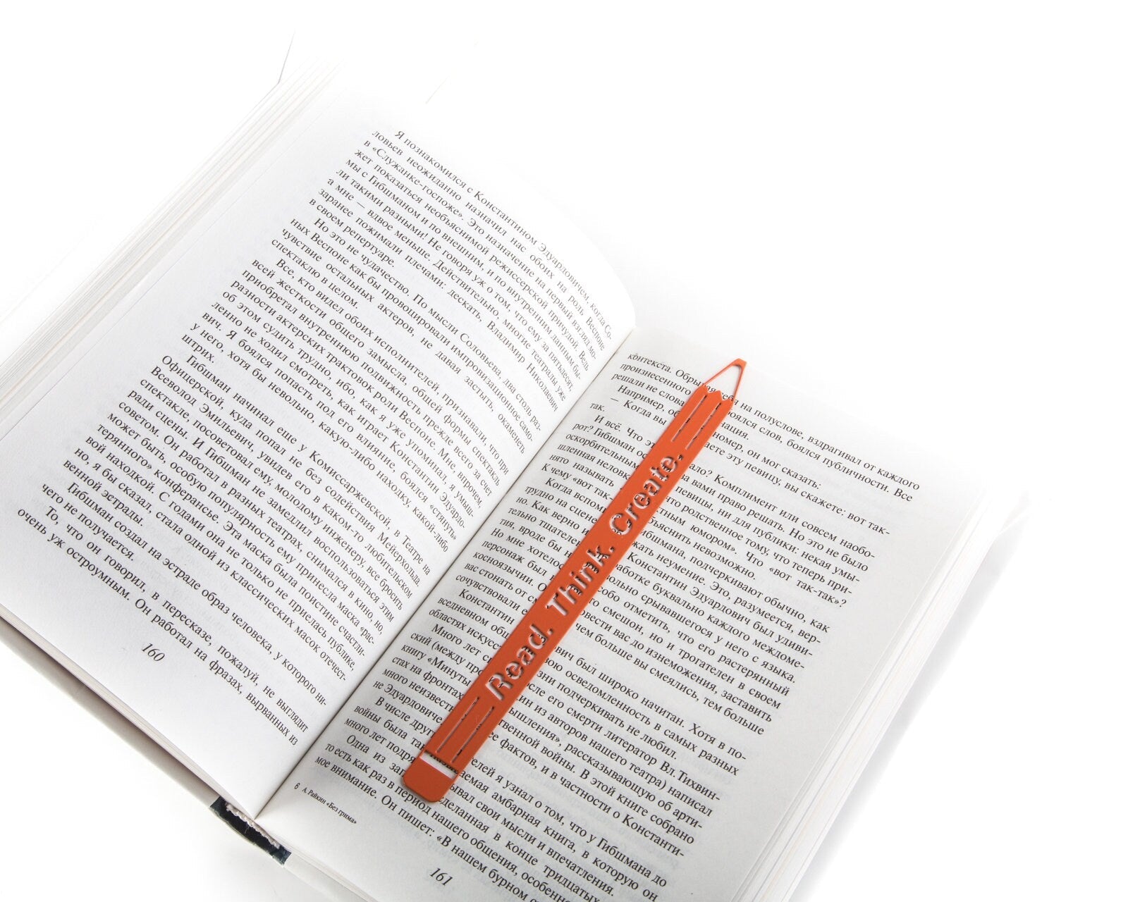 Read. Think. Create. Pencil metal bookmark in red resting on the pages of an open book