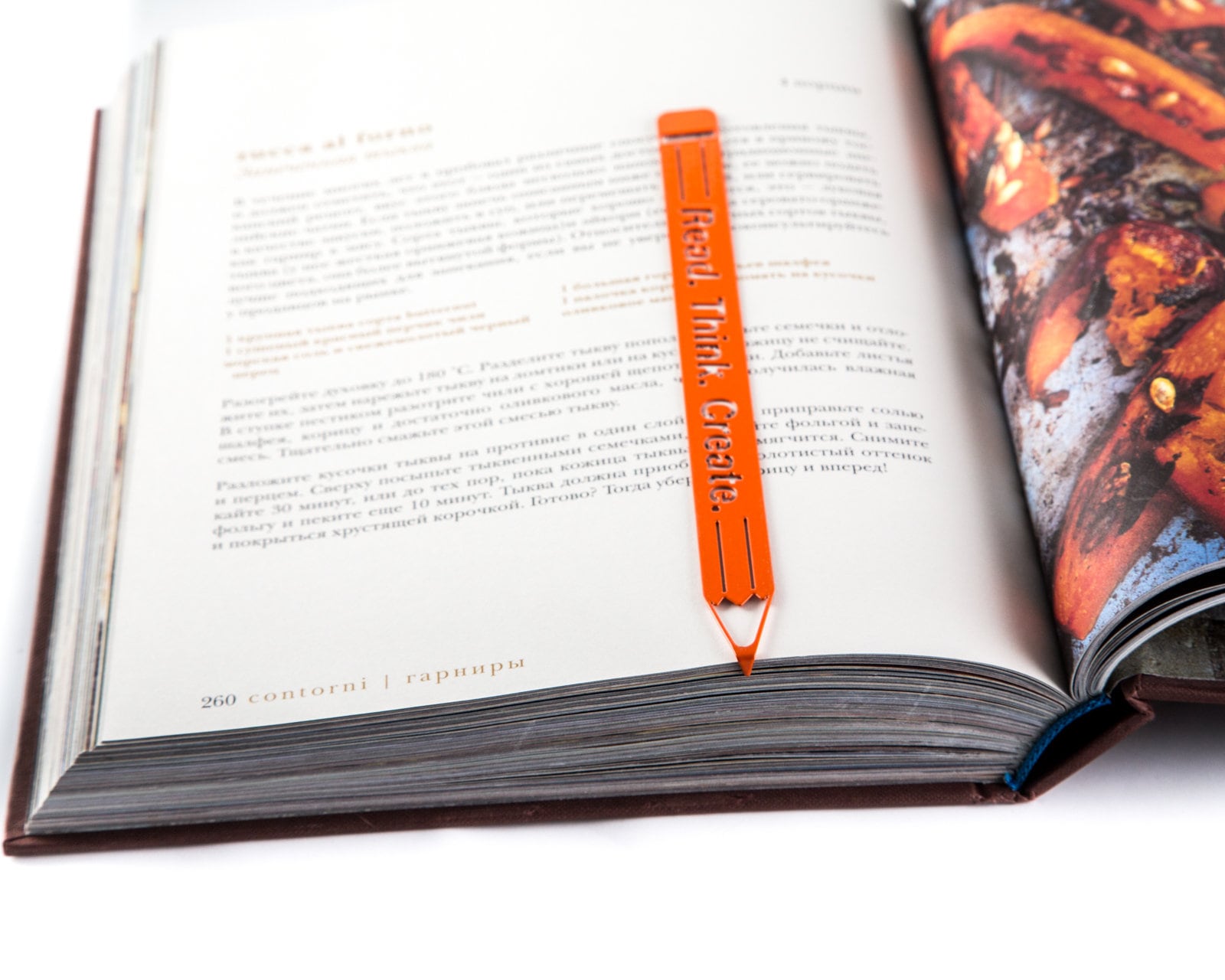 Read. Think. Create. Pencil metal bookmark in red marking a page in an open book