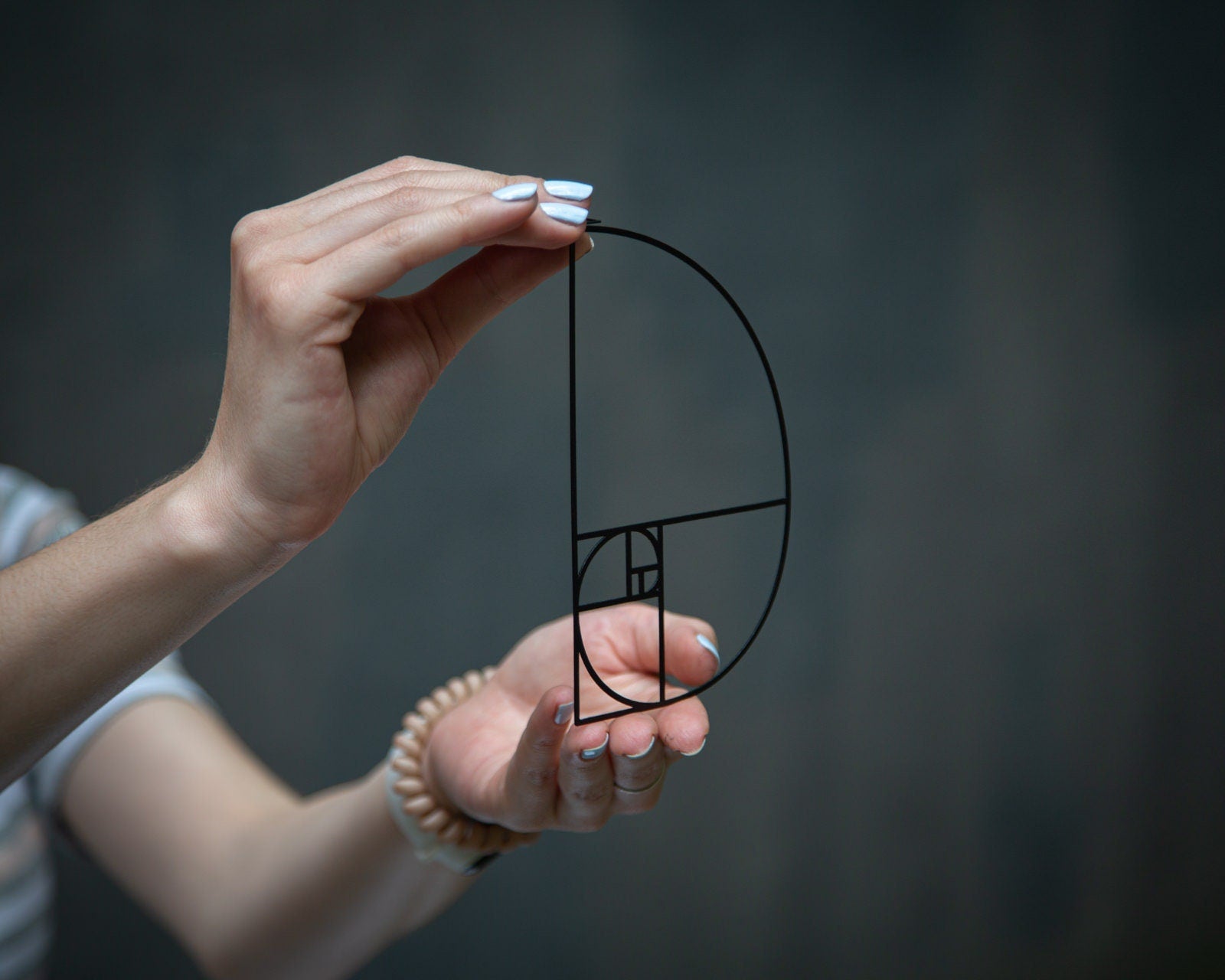 Golden Ratio metal bookmark — hands hold bookmark on white