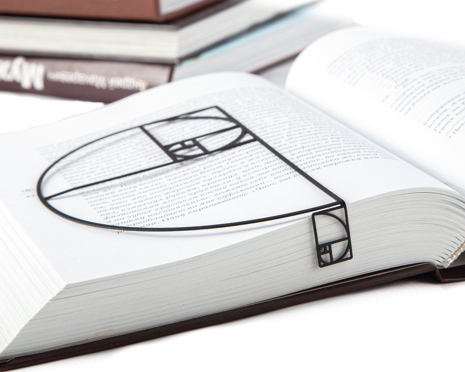 Golden Ratio metal bookmark marking a page in an open book