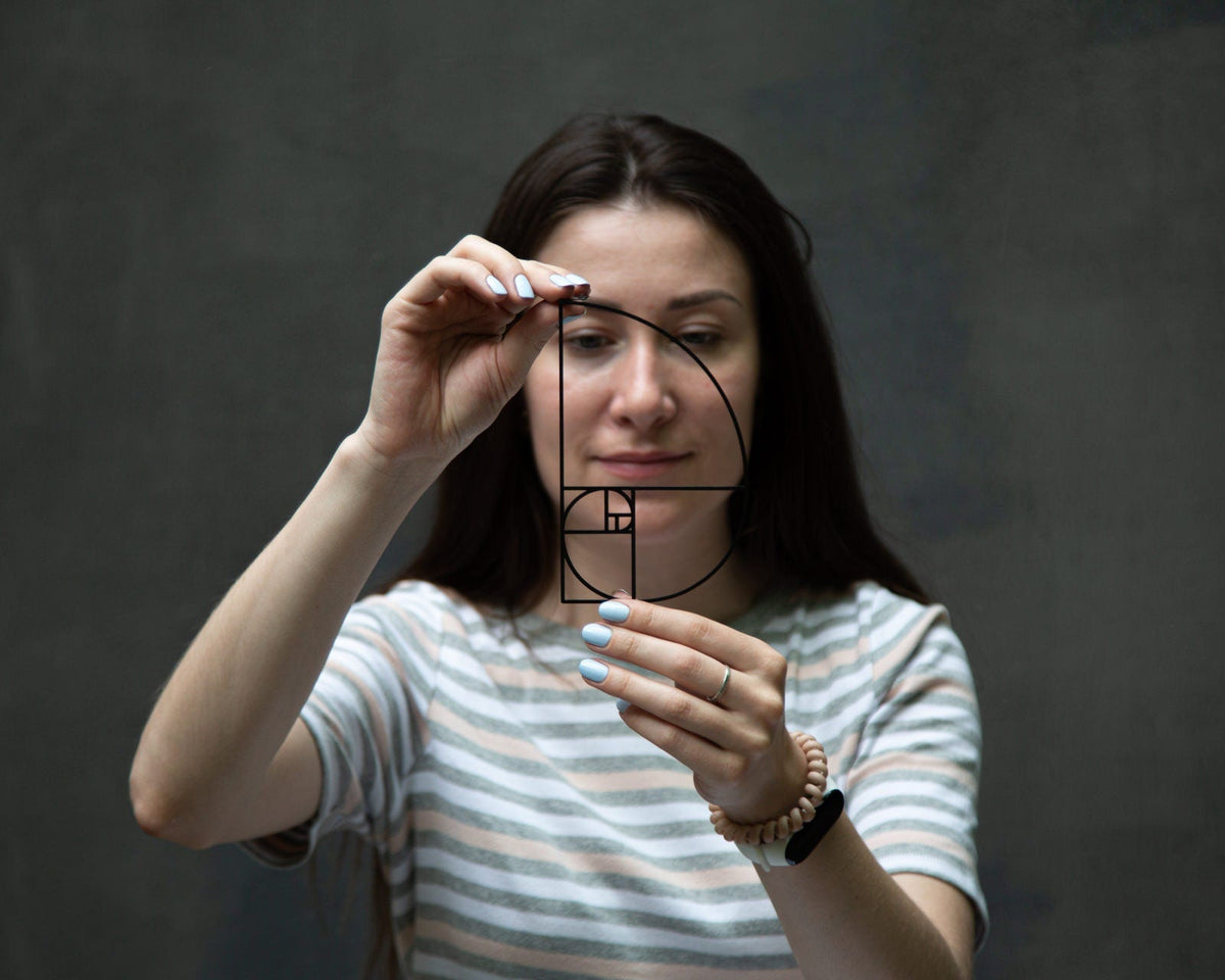 Golden Ratio metal bookmark — woman holds bookmark to her eye