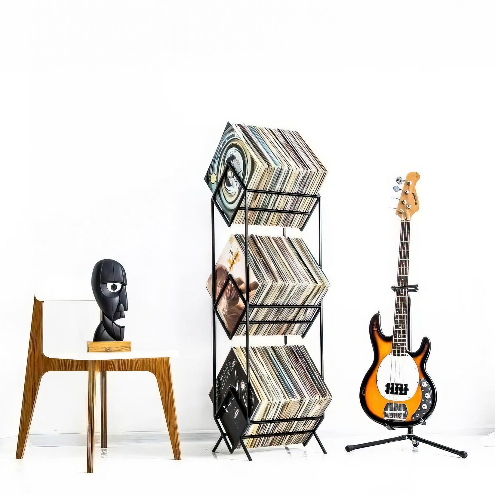 three-tier vinyl record stand by a guitar and a char with black head sculpture Division bell.