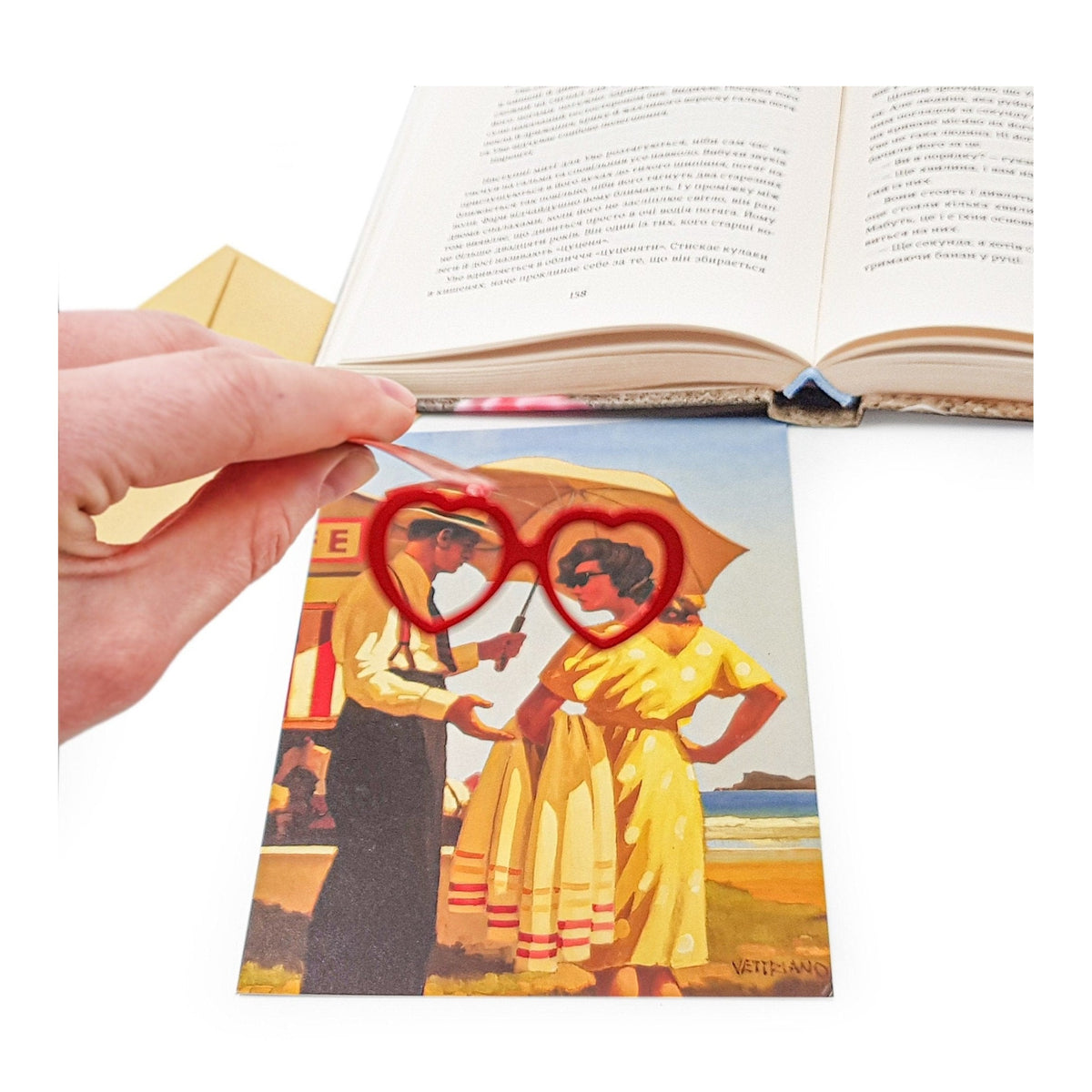 Vision Love metal bookmark in red marking a page in an illustrated book