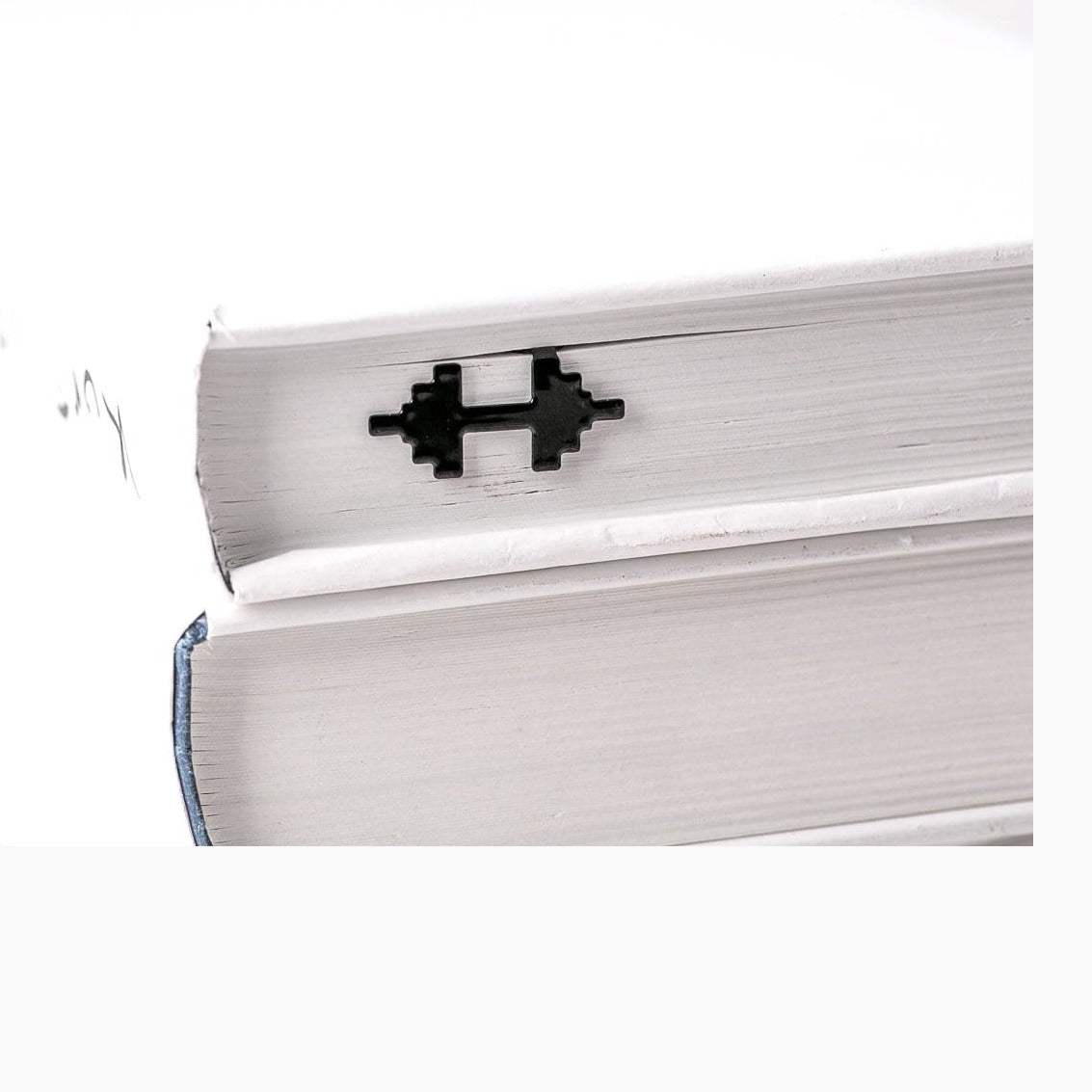 Weights metal bookmark in a closed book, only its top showing above the pages