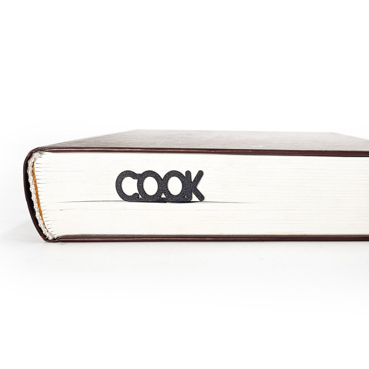 Whisk metal bookmark in a closed book, only its top showing above the pages