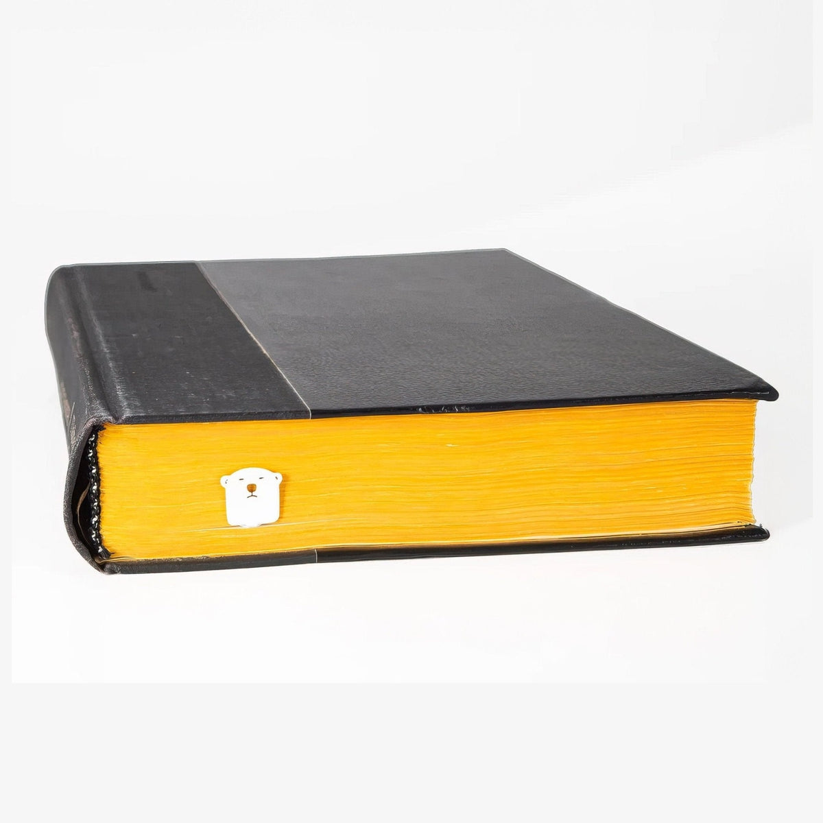 White Bear metal bookmark in white in a closed book, only its top showing above the pages