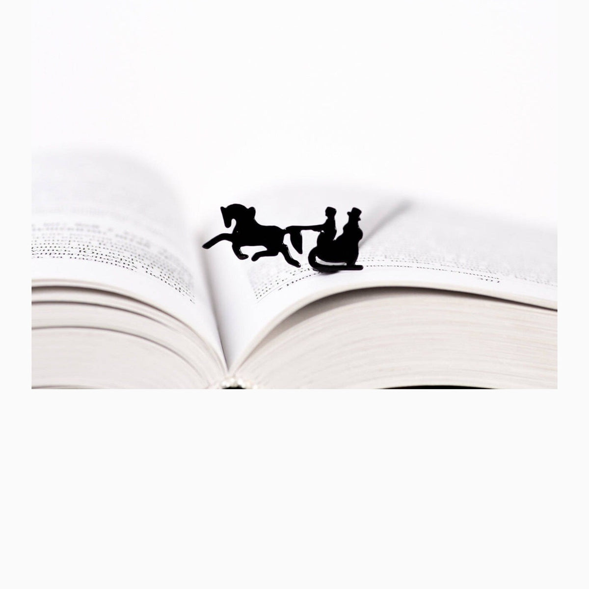 Winter Sleigh metal bookmark resting on the pages of an open book