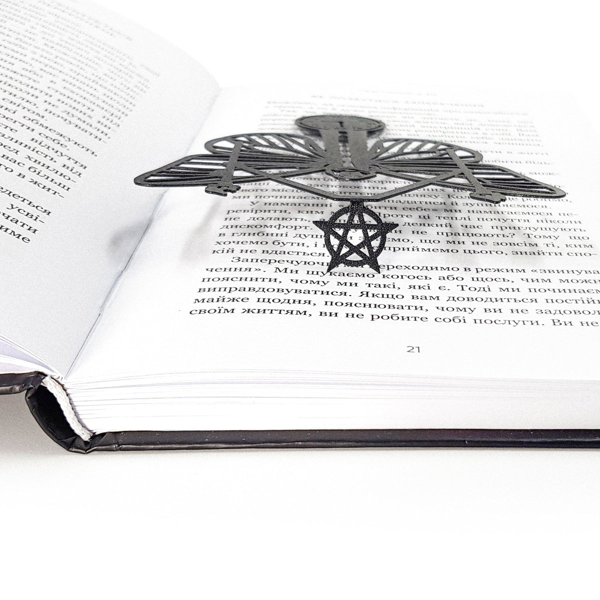 Witch Hour metal bookmark resting on the pages of an open book