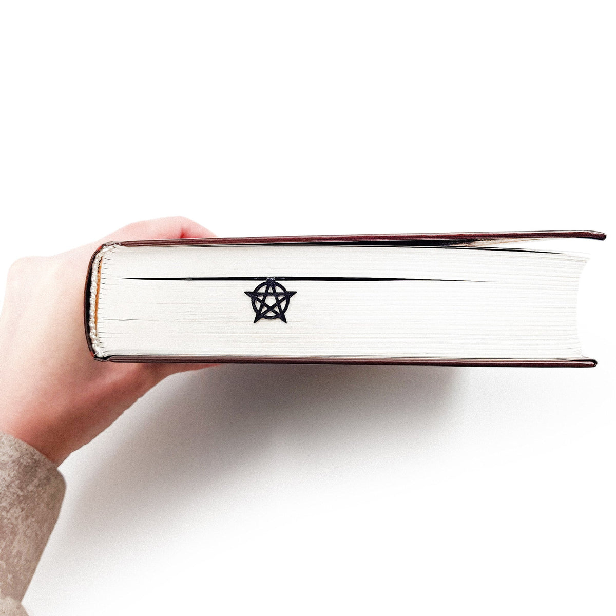 Witch Hour metal bookmark held up beside an open book