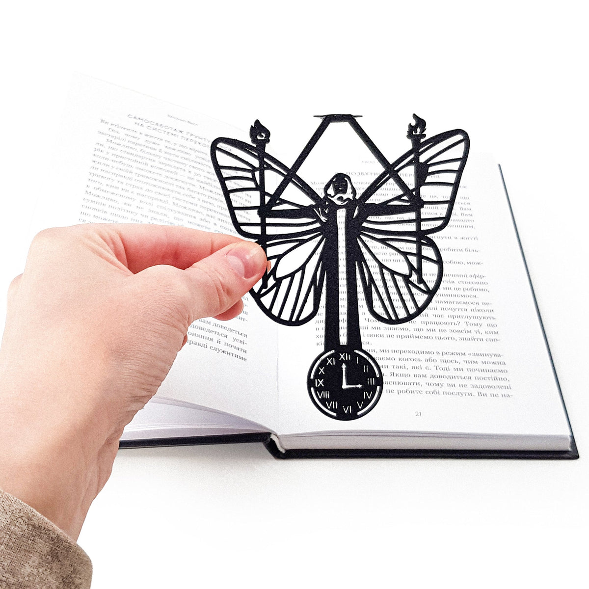 Witch Hour metal bookmark held over a book, seen from the front