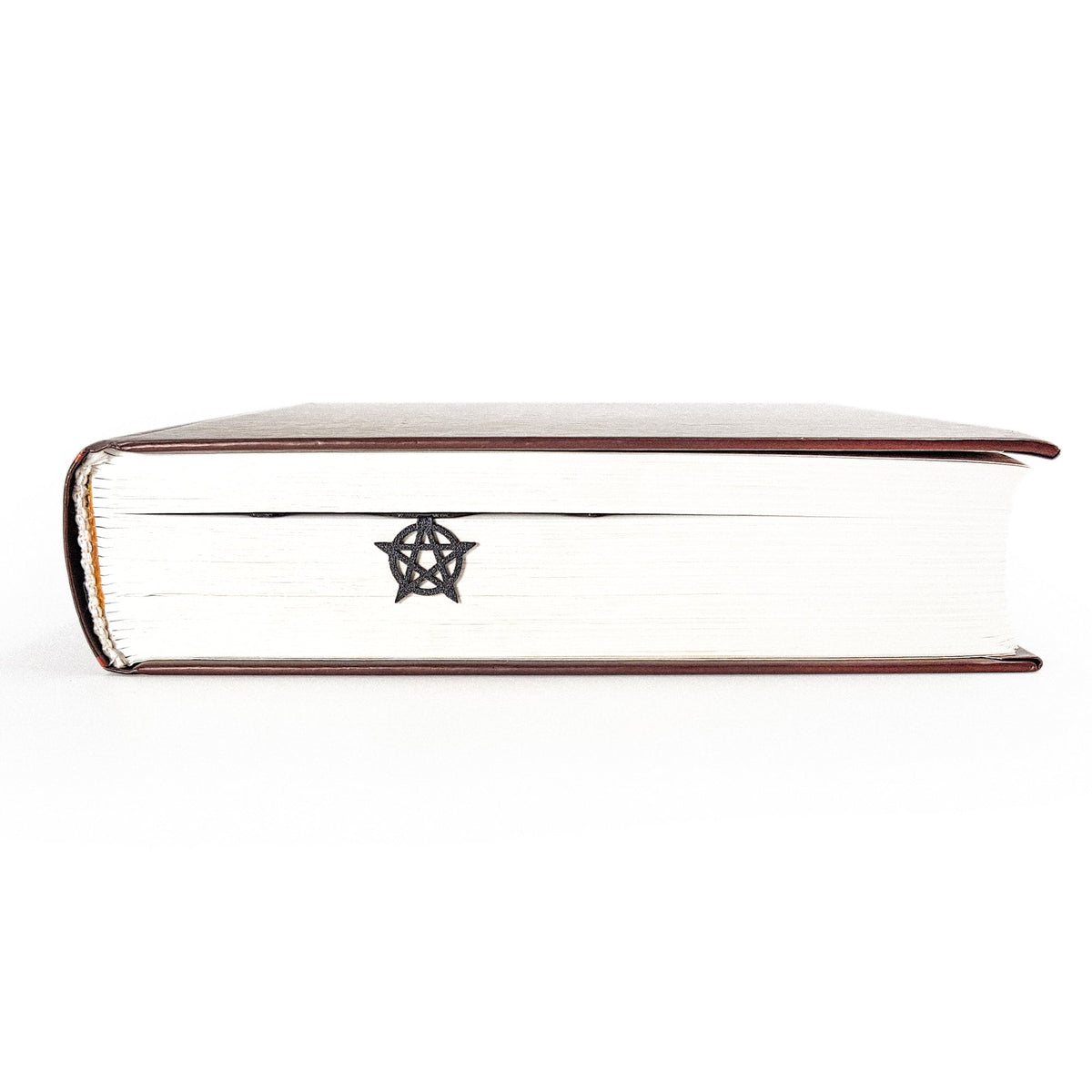 Witch Hour metal bookmark in a closed book, only its top showing above the pages