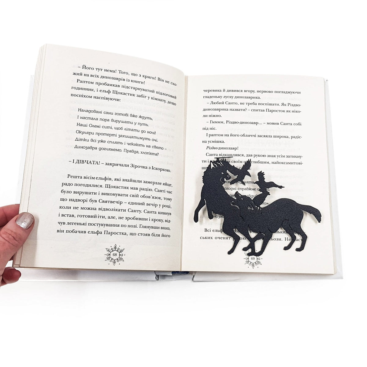 Wolves & Raven metal bookmark lying across the pages of an open book
