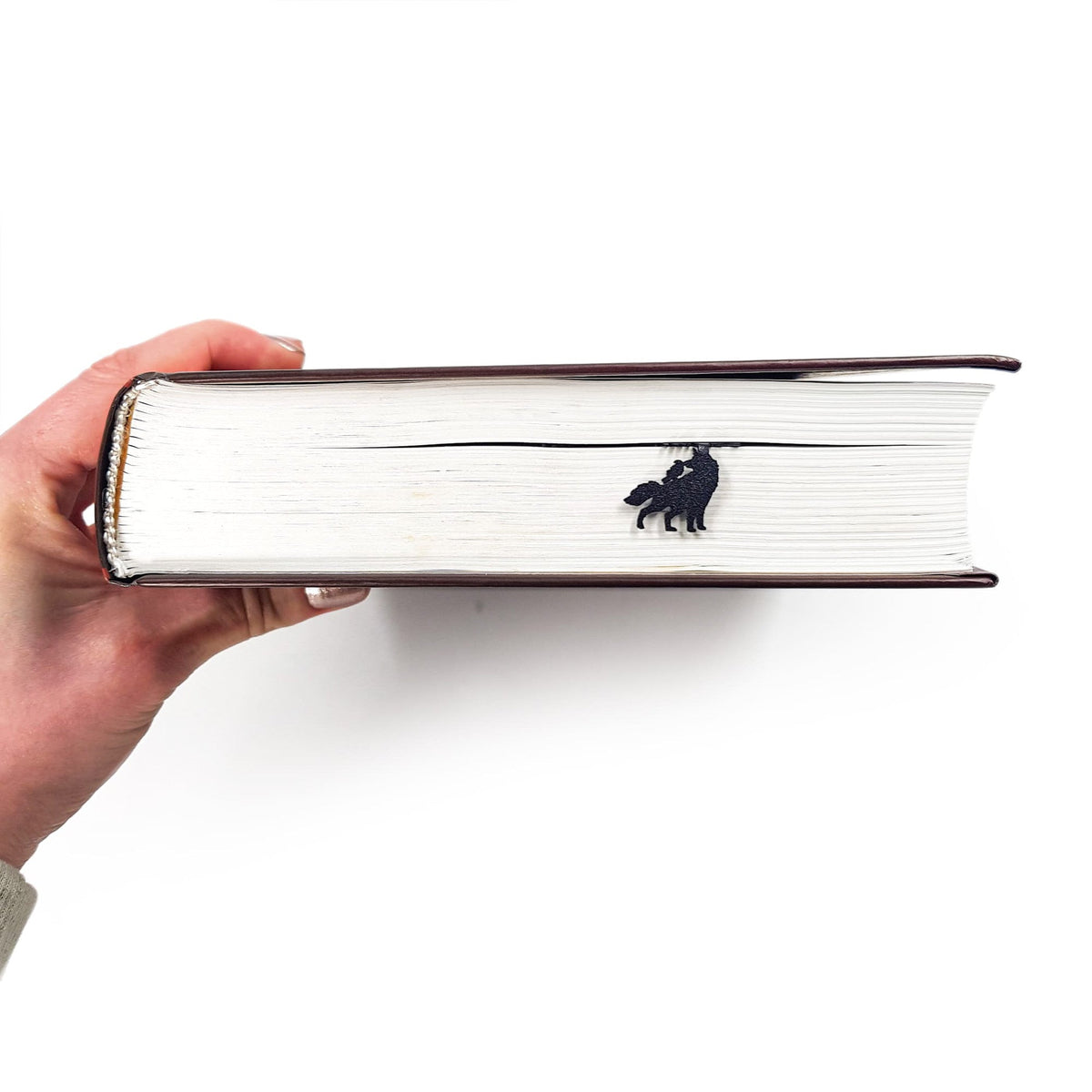 Wolves & Raven metal bookmark held in a hand to show its size