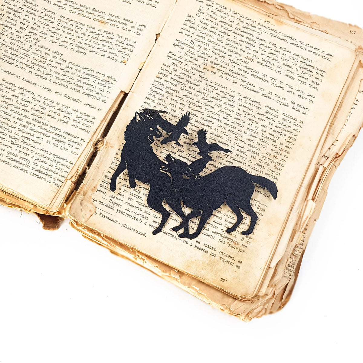 Wolves & Raven metal bookmark resting on the pages of an open book