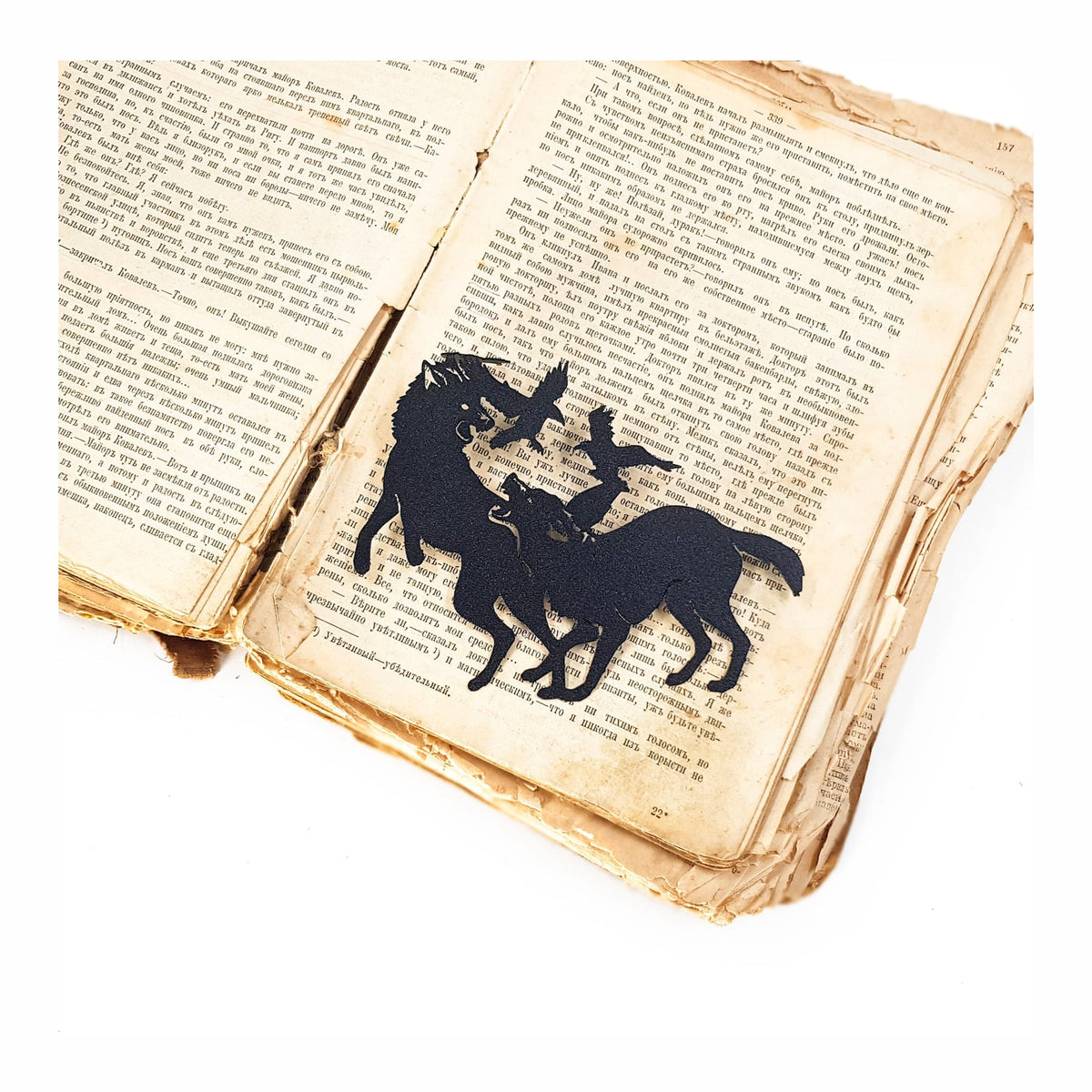 Wolves & Raven metal bookmark resting on the pages of an open book