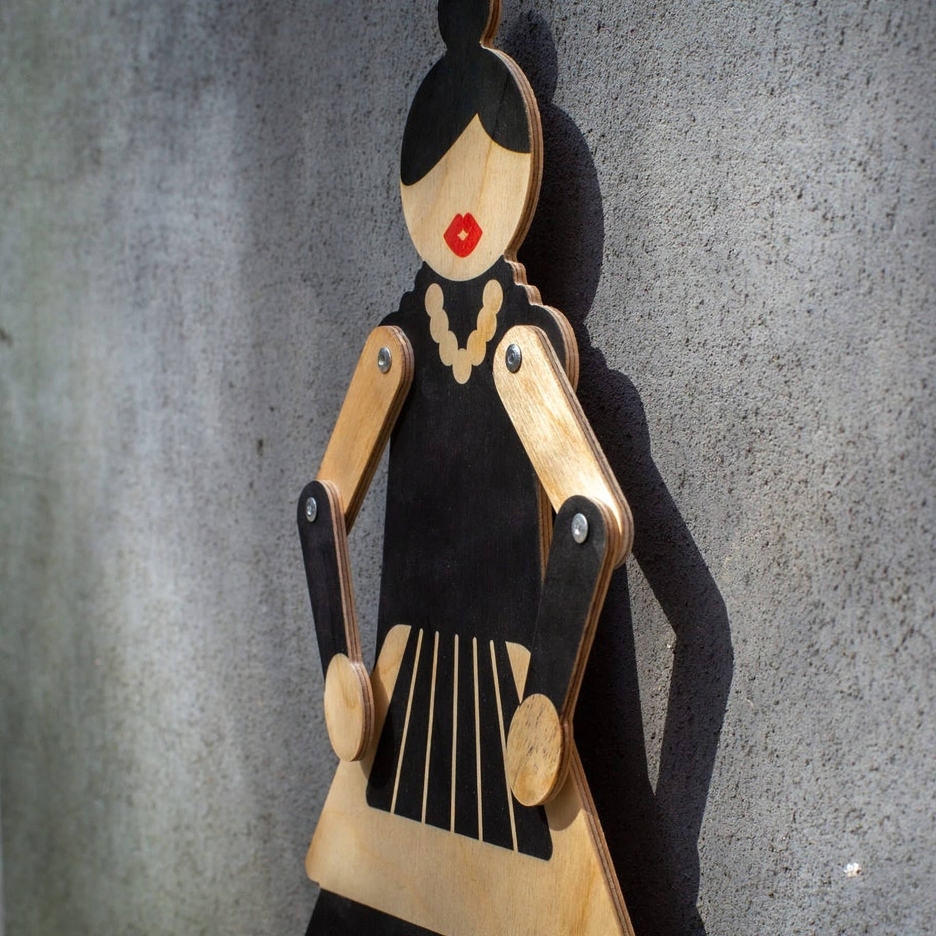 Flamenco wooden puppet on grey wall — face detail with red lips, pearl necklace and shadow