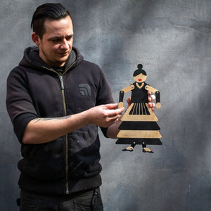 Maker holding wooden flamenco puppet showing full figure and scale against grey wall